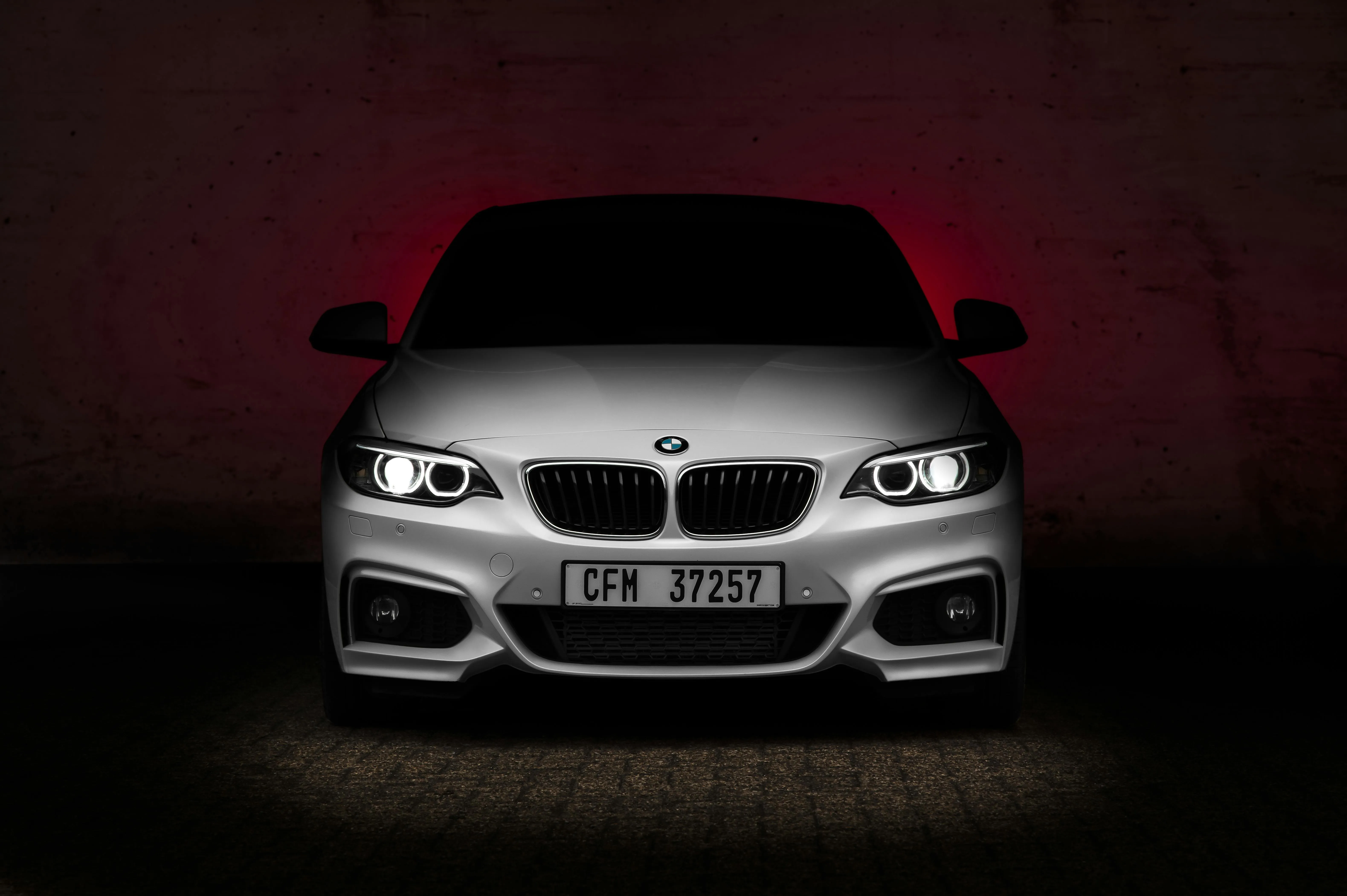 Aggressive Bmw with Headlights on in Dark Studio Image