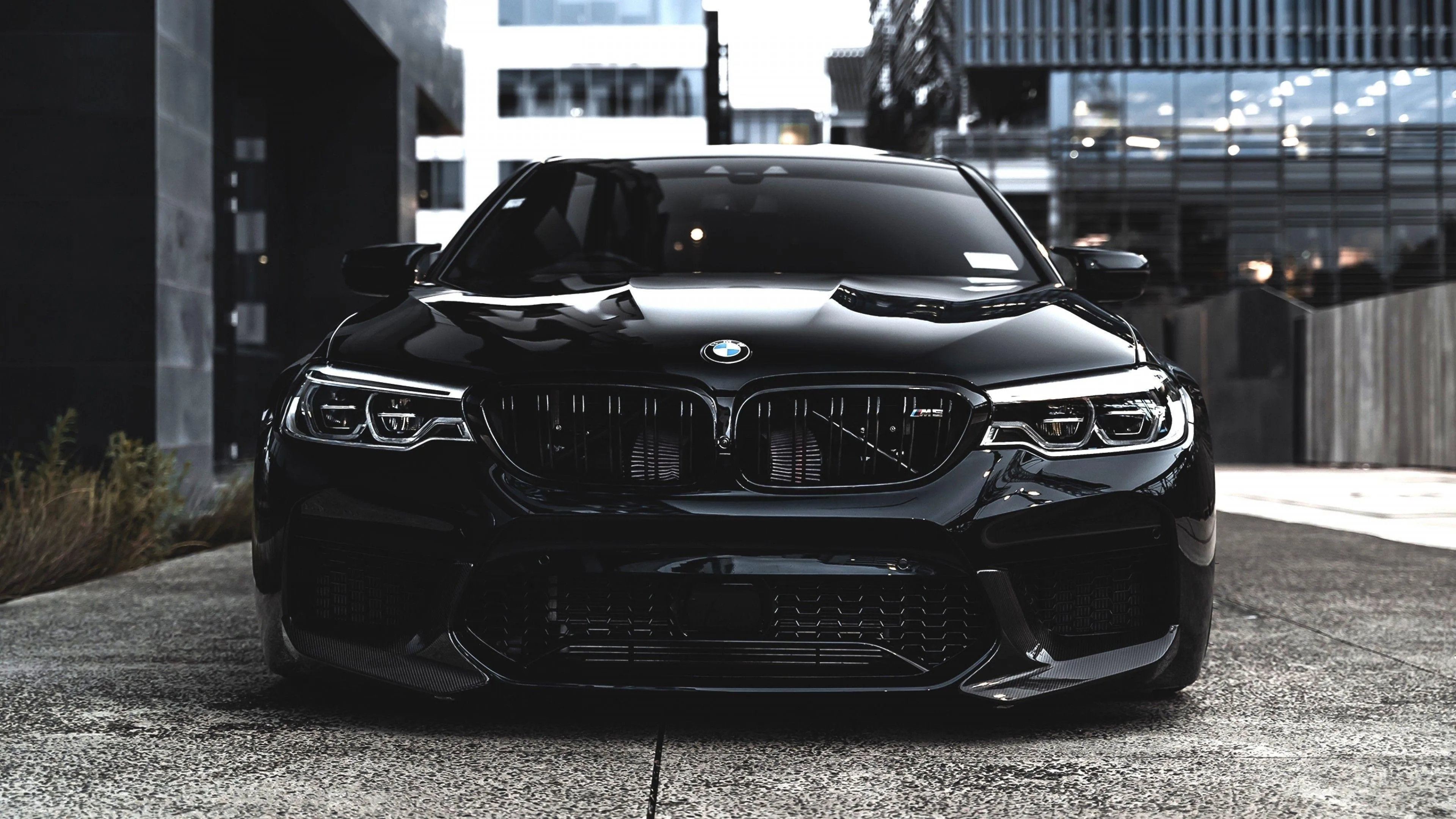 Black Bmw Parked at Night Near Building with Strong Shadows