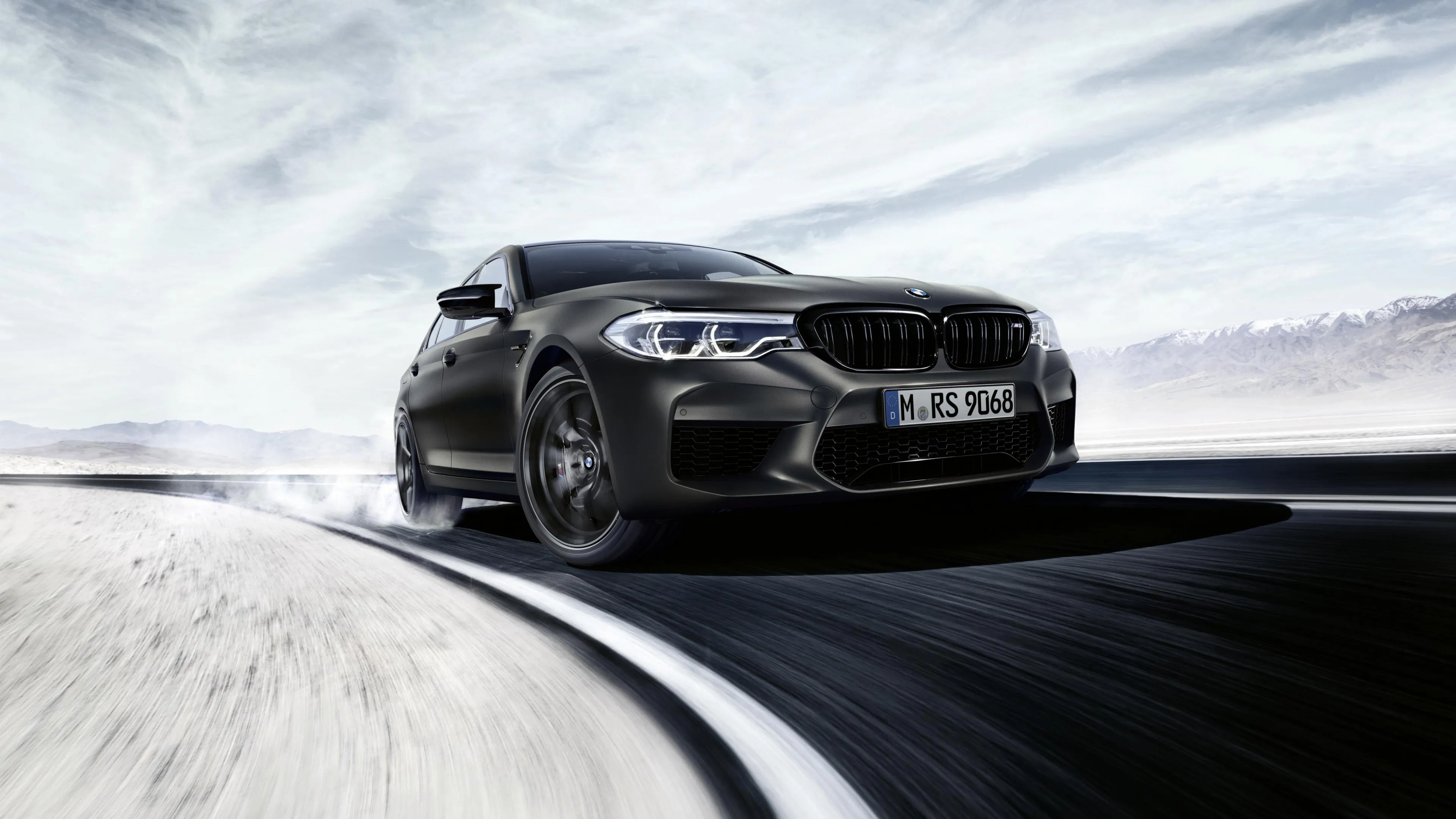 Black Bmw Speeding on a Snowy Mountain Road Hd Image