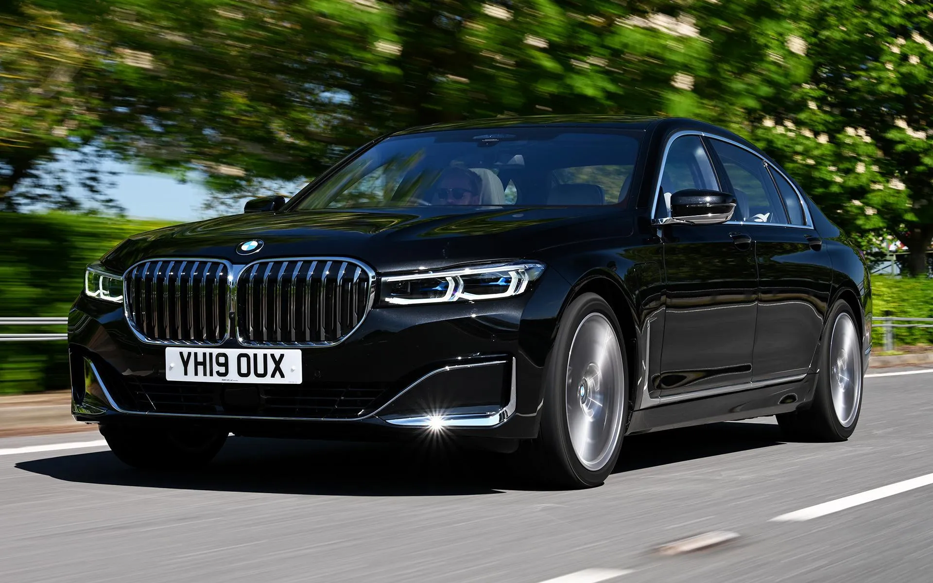 Black Bmw Suv Driving Along Road Lined with Green Trees