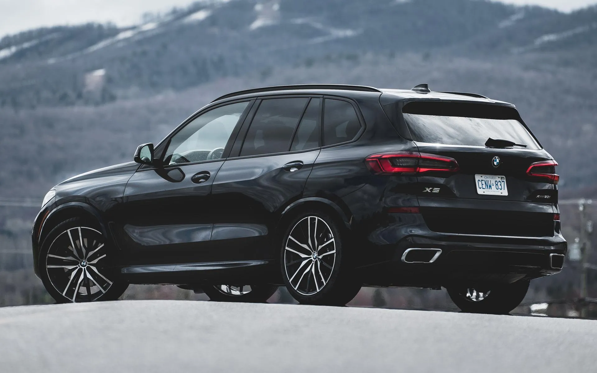 Black Bmw Suv Driving on Open Road with Mountains Behind
