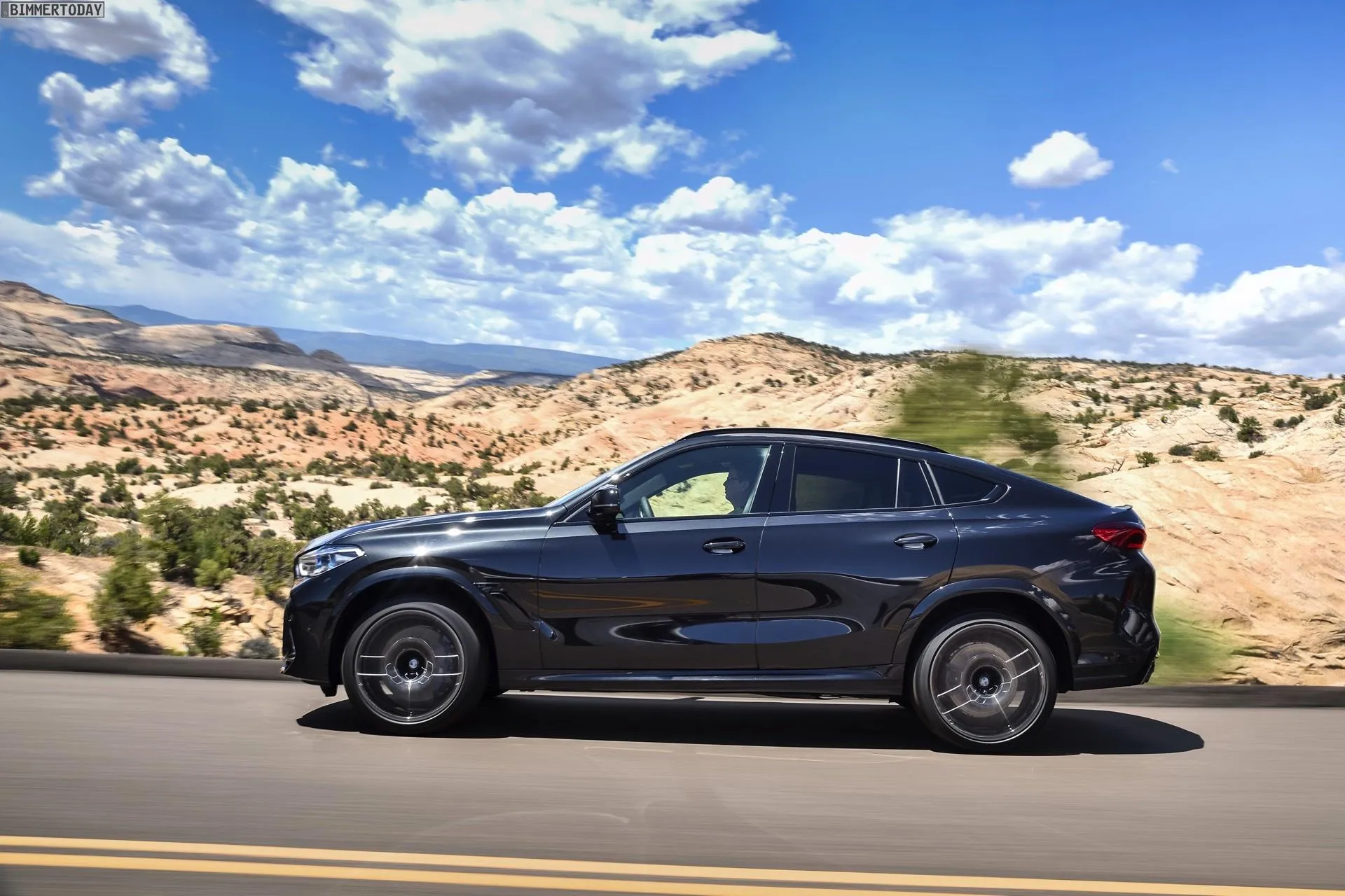 Black Bmw Suv Driving Through Rocky Desert Landscape
