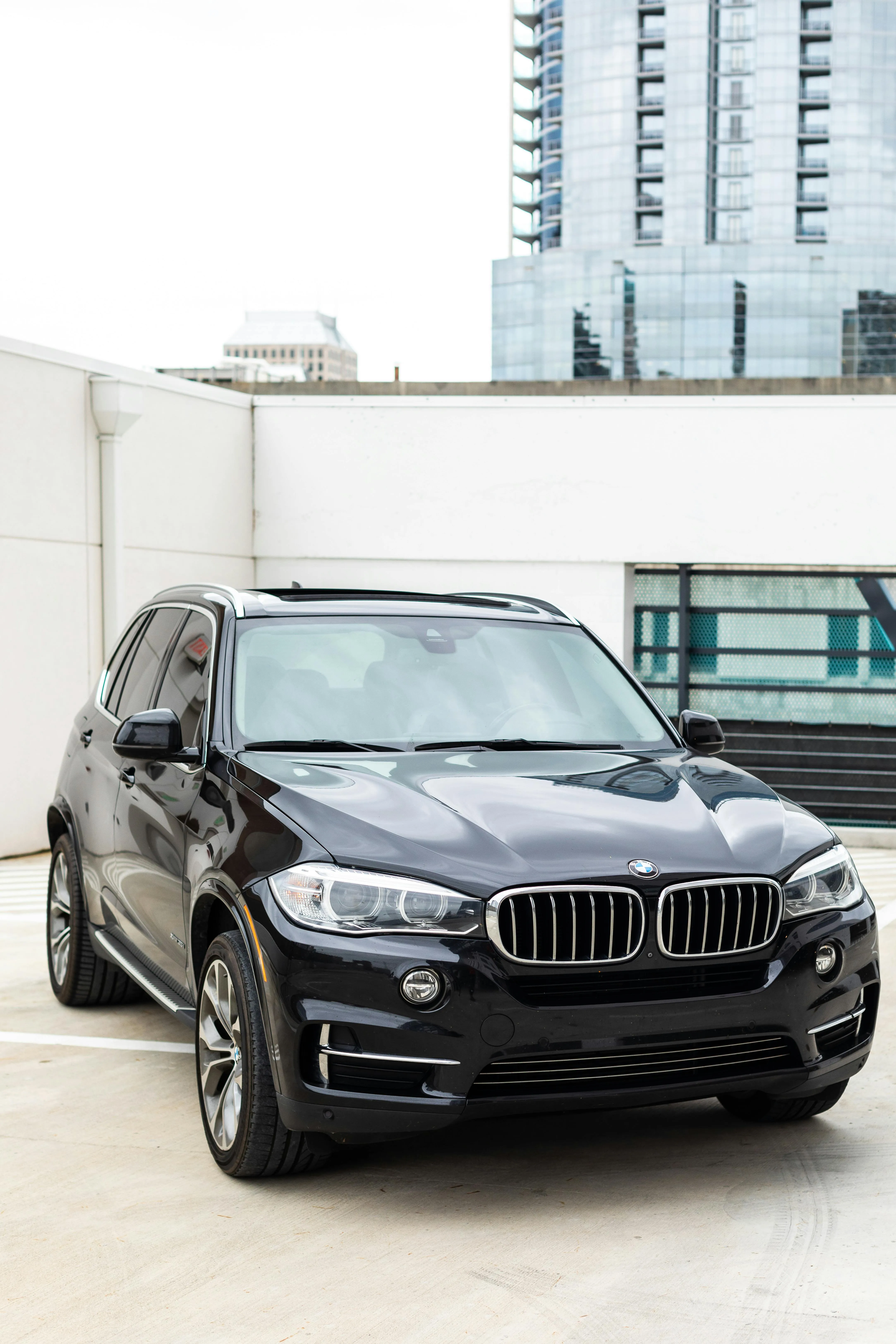 Black Bmw Suv Parked on Rooftop with Buildings Behind