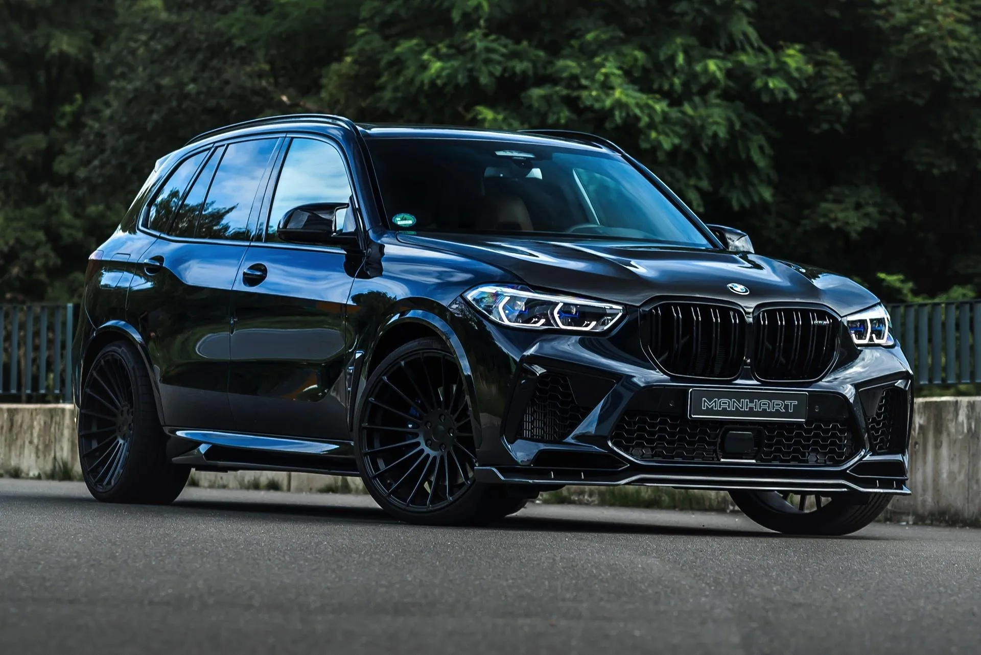 Black Bmw X Series Parked in Front of Lush Greenery