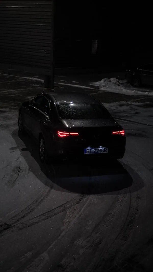 Black Mercedes Benz Driving Alone in Dark Snowy Road