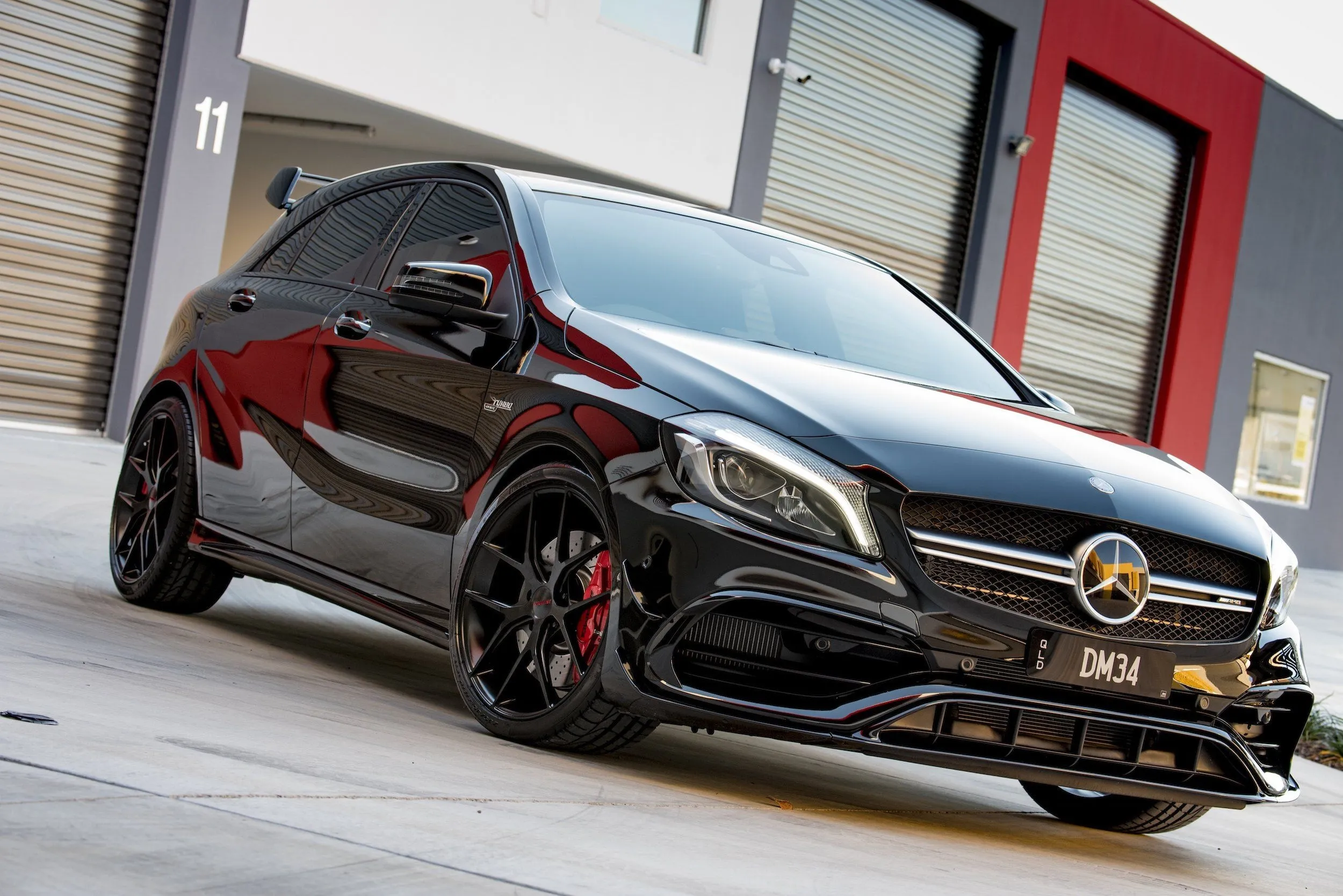 Black Mercedes Benz Sports Car Parked Outside Red Building