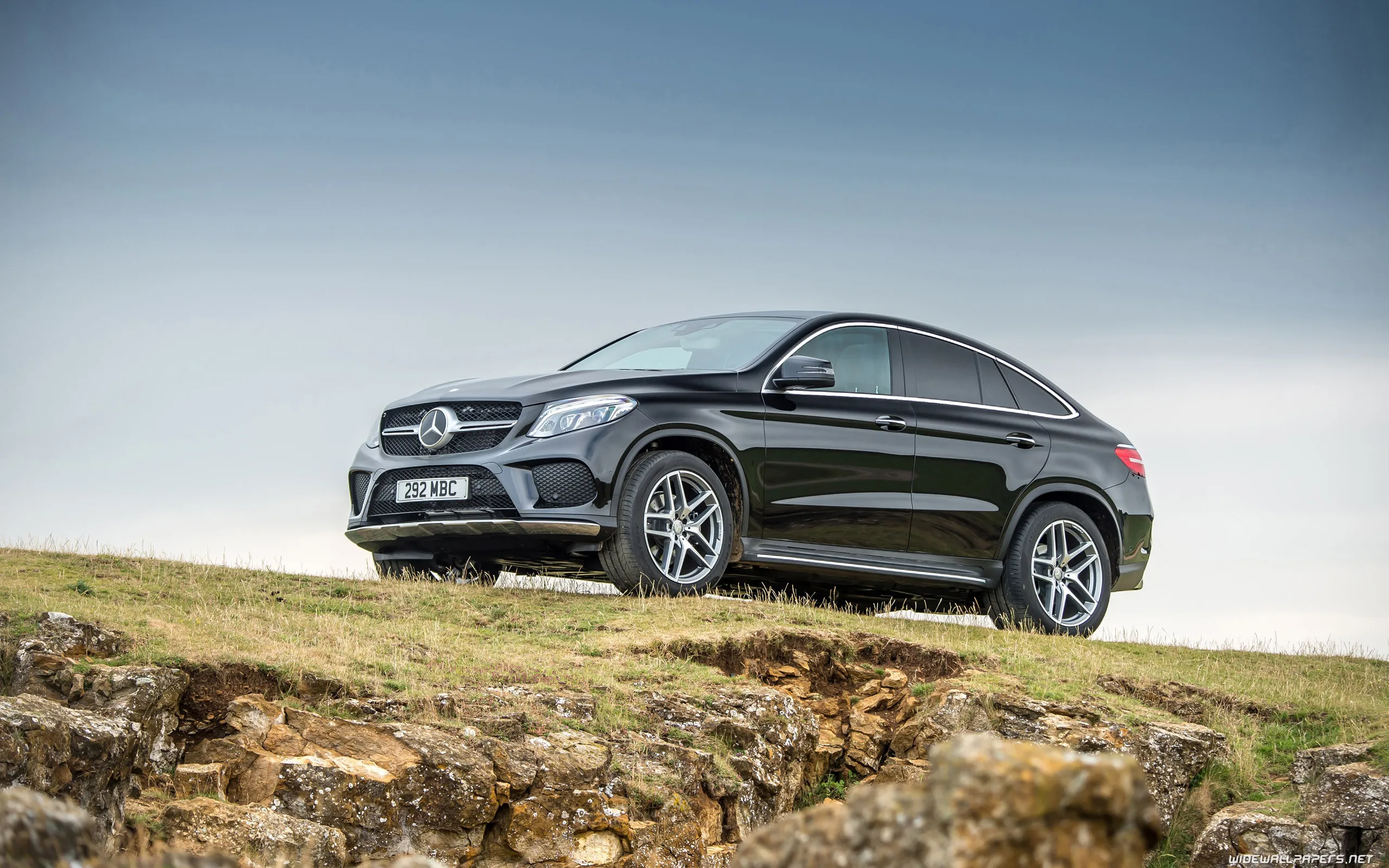 Black Mercedes Coupe Parked on Hill with Blue Sky View