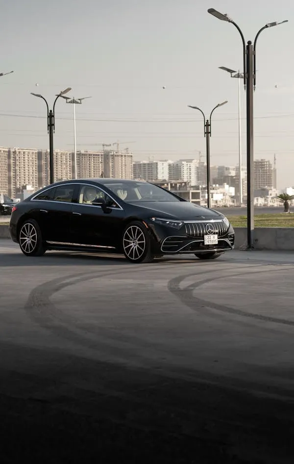 Black Mercedes Driving in Open City Space free Wallpaper