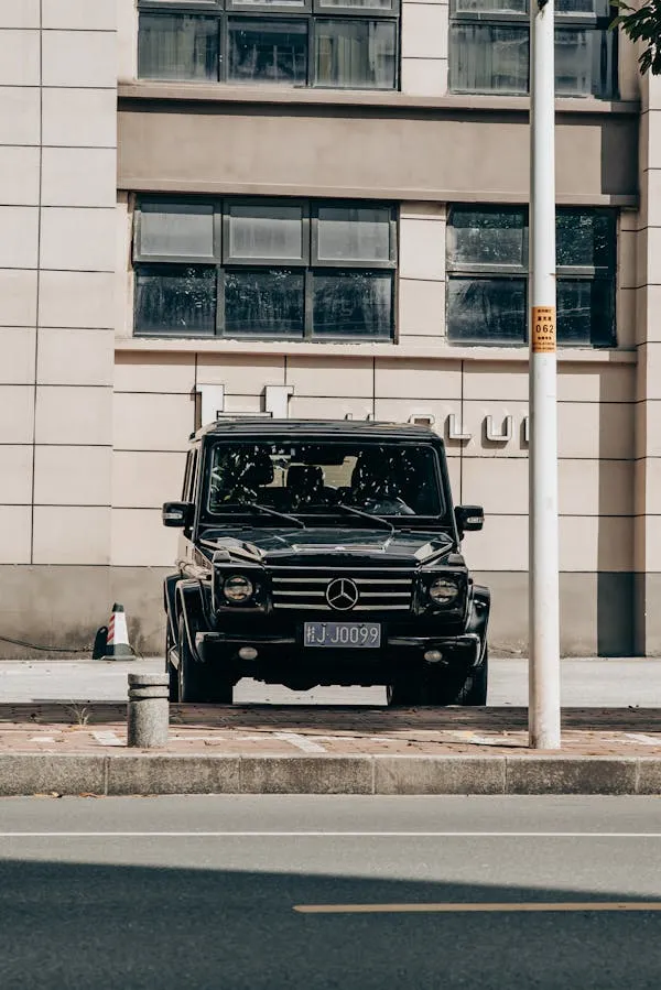Black Mercedes G Class parked in front of office tower