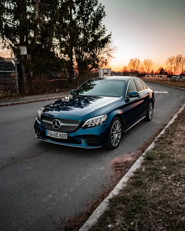 Black Mercedes parked on roadside with evening sunlight