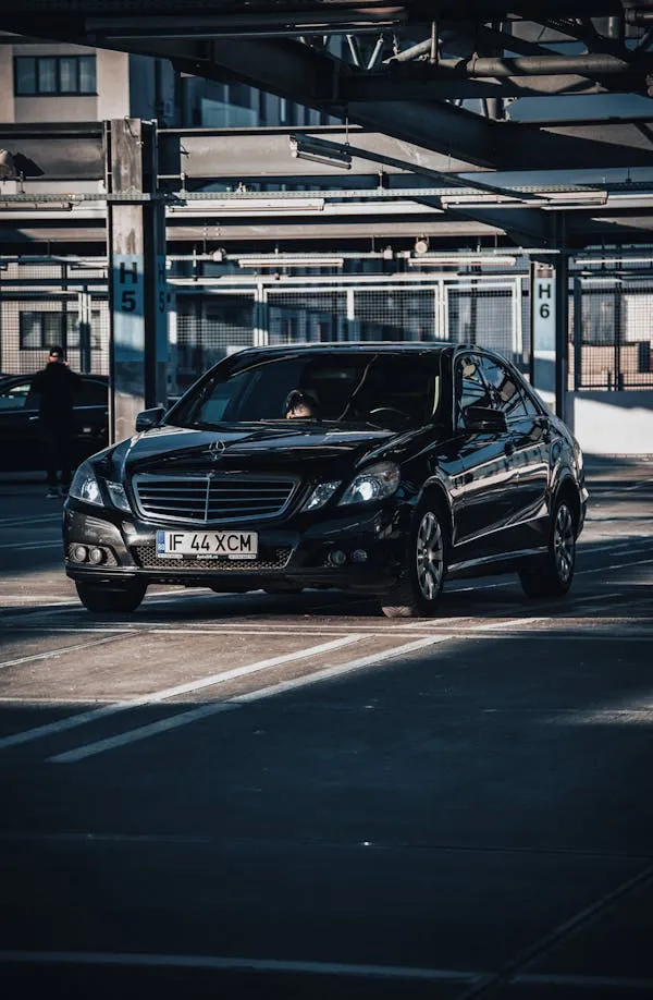 Black Mercedes sedan parked in shaded urban parking lot