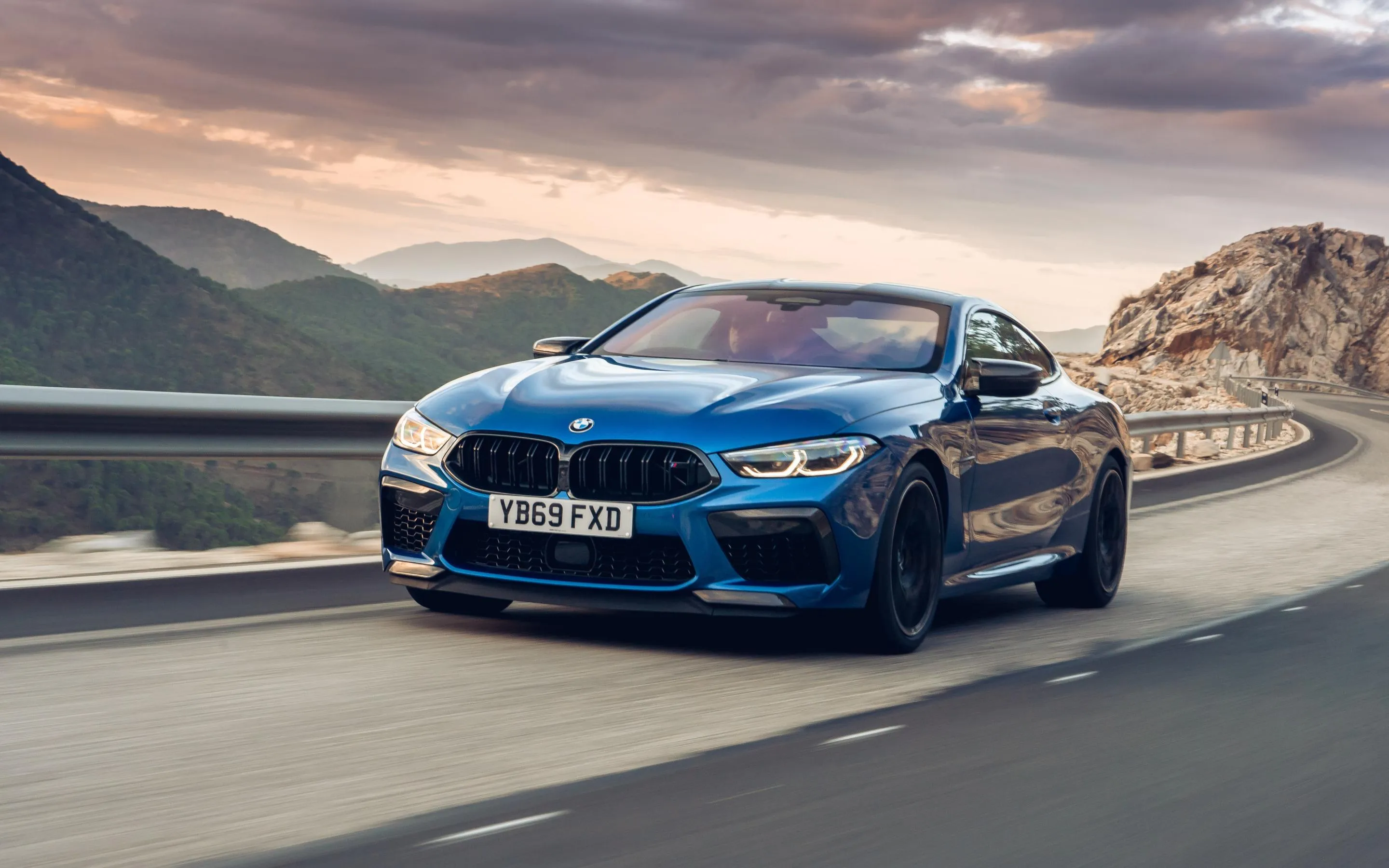 Blue Bmw Coupe Driving on Road with Pink Sky and Mountains