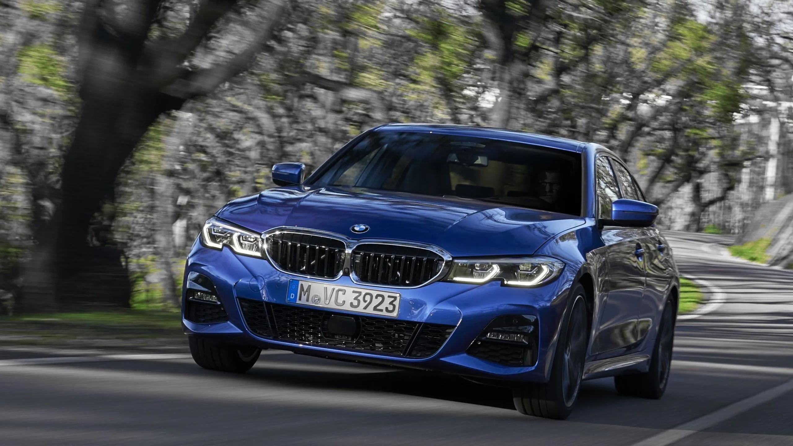 Blue Bmw Driving Along Tree Lined Road in Spring Wallpaper