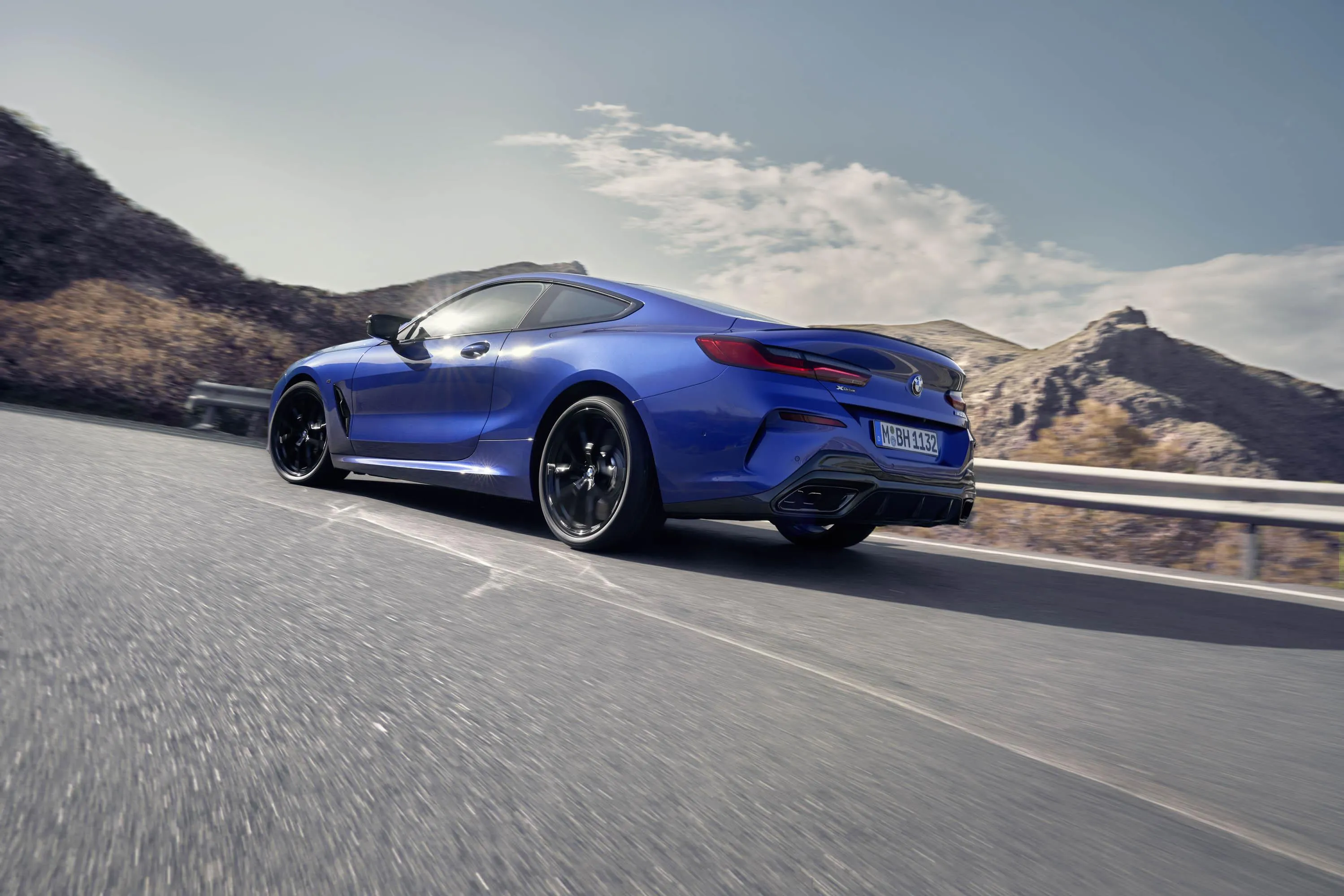 Blue Bmw Driving Fast on a Scenic Open Road with Hills Behind
