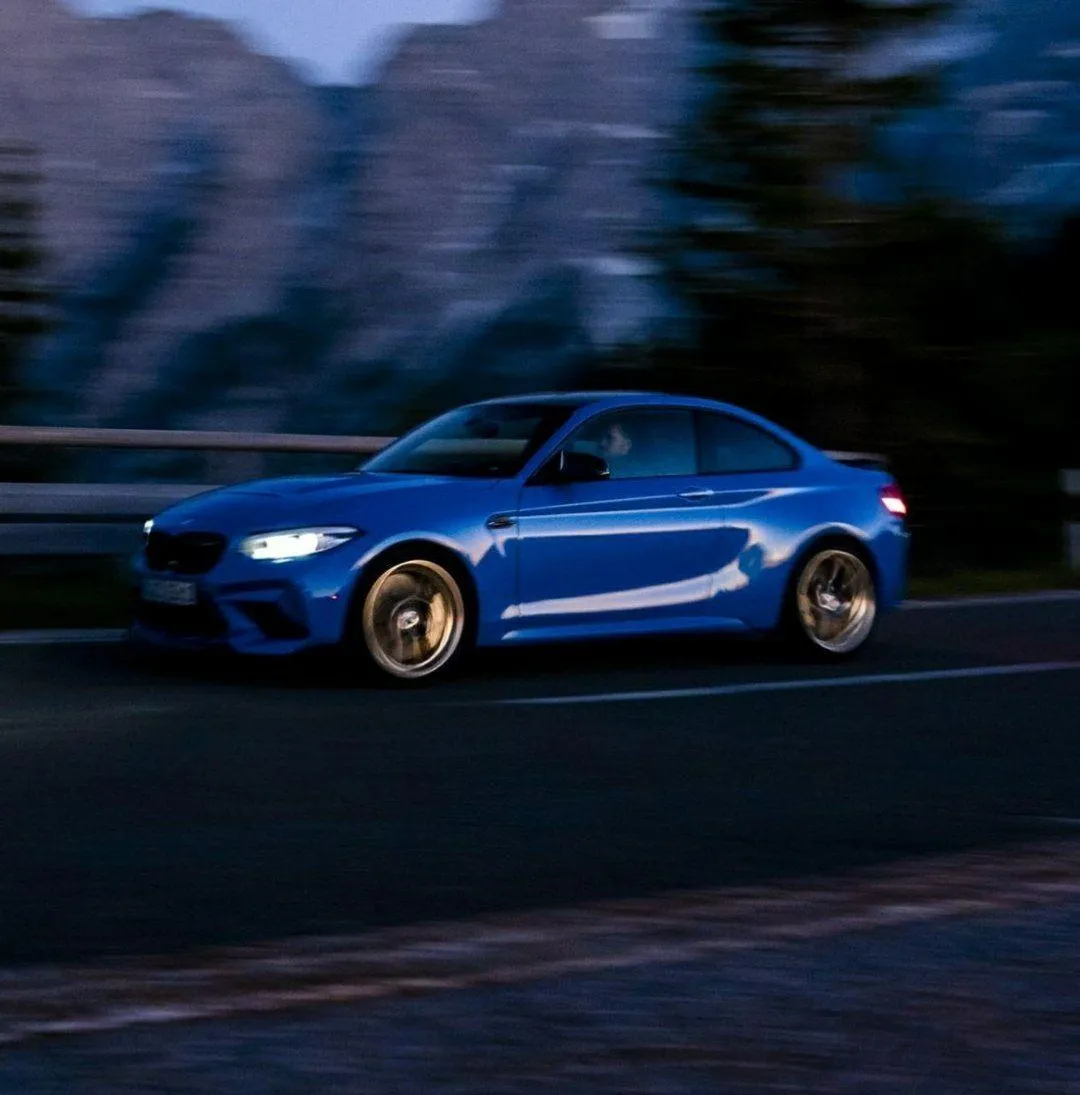 Blue Bmw Driving Fast on Road with Mountains in Background