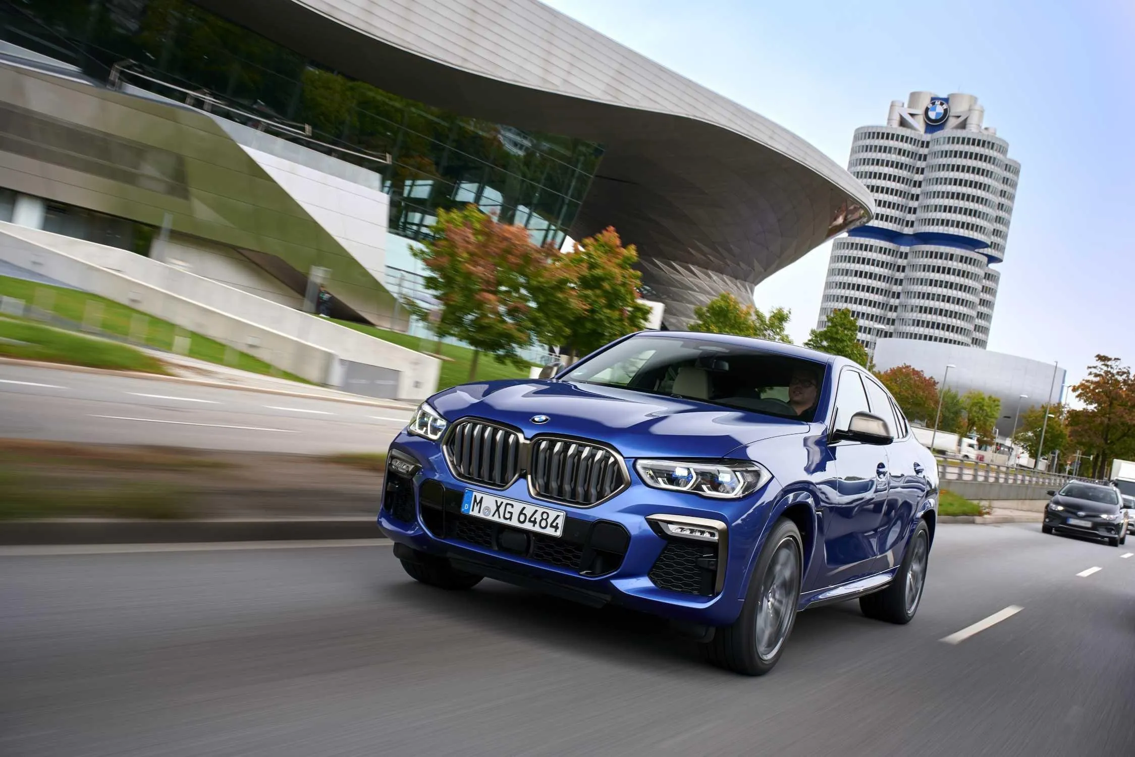 Blue Bmw M Series Driving Past Modern City Buildings