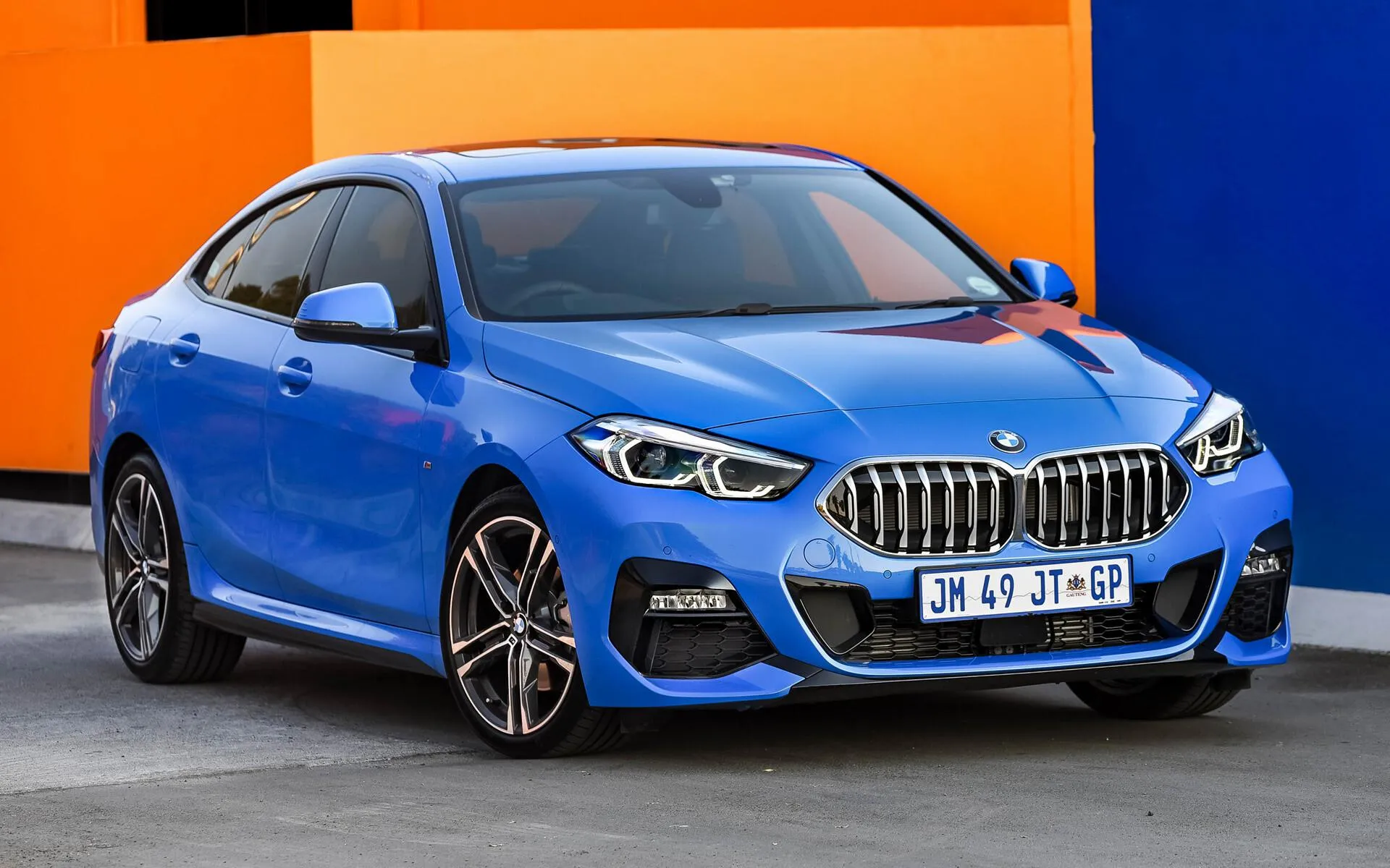 Blue Bmw Parked Against a Bright Orange and Blue Wall