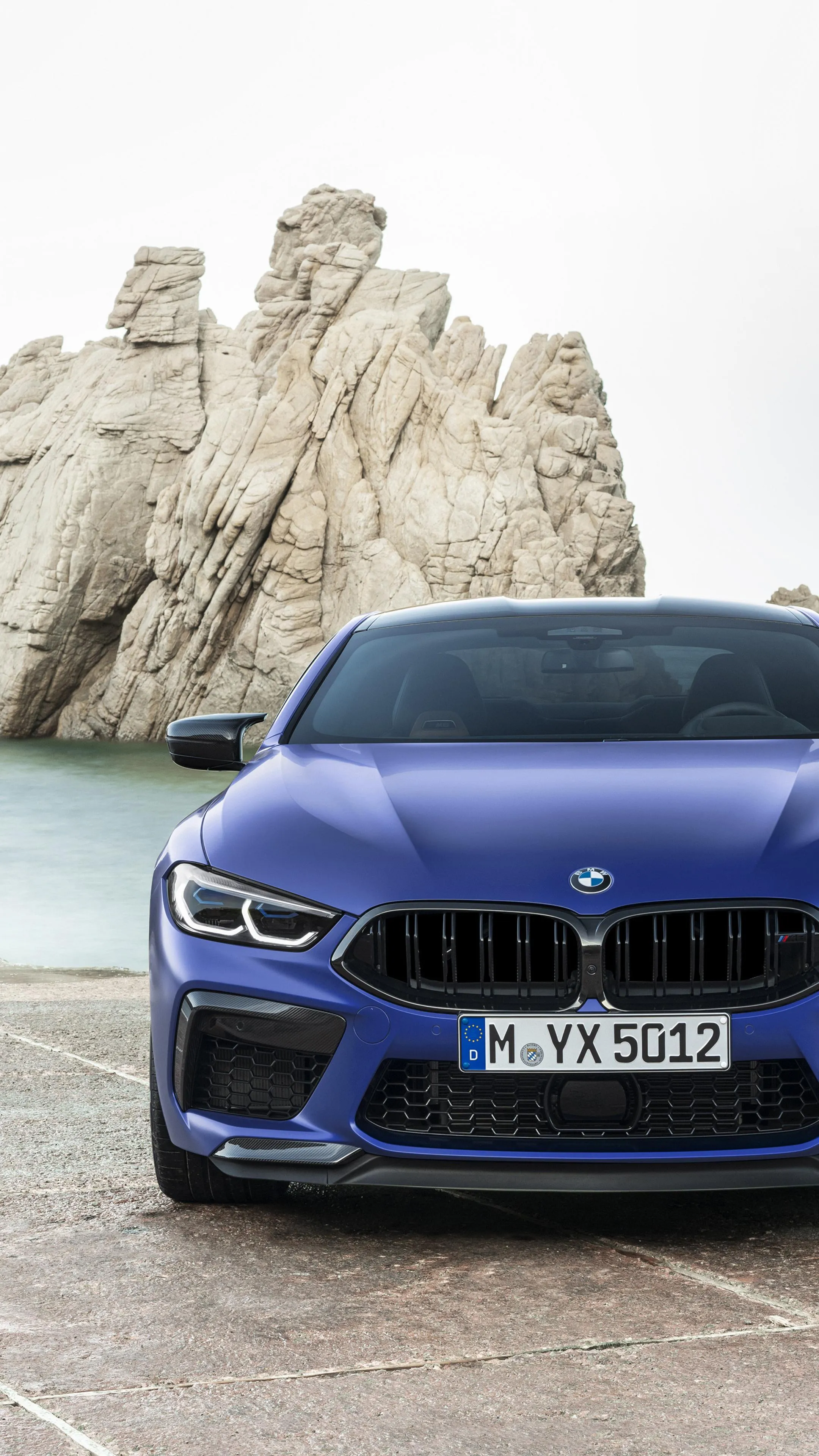 Blue Bmw Parked Near Rocky Cliffs with Cloudy Skies