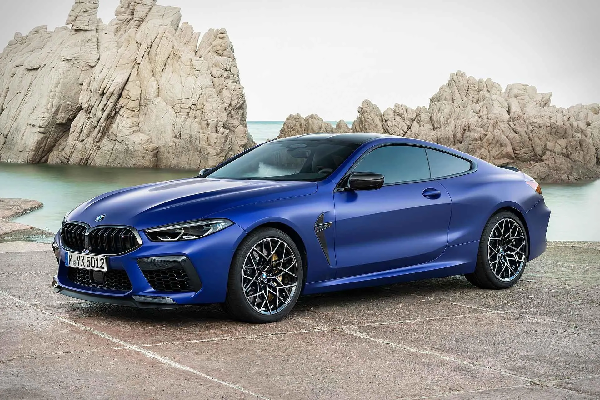 Blue Bmw Parked on Beach Road Near Rocky Landscape Image