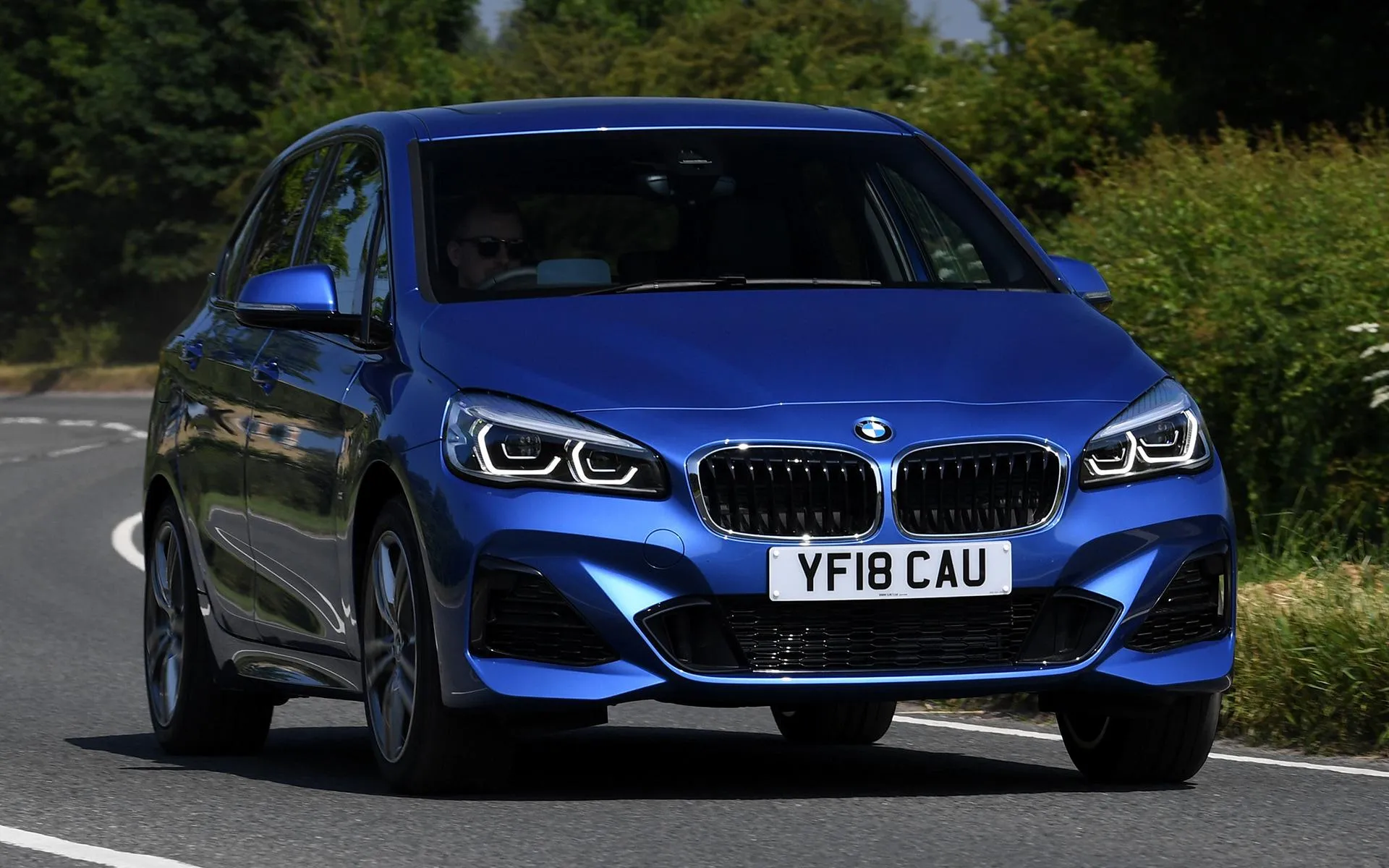 Blue Bmw Parked on Grass Beside Trees and a Building
