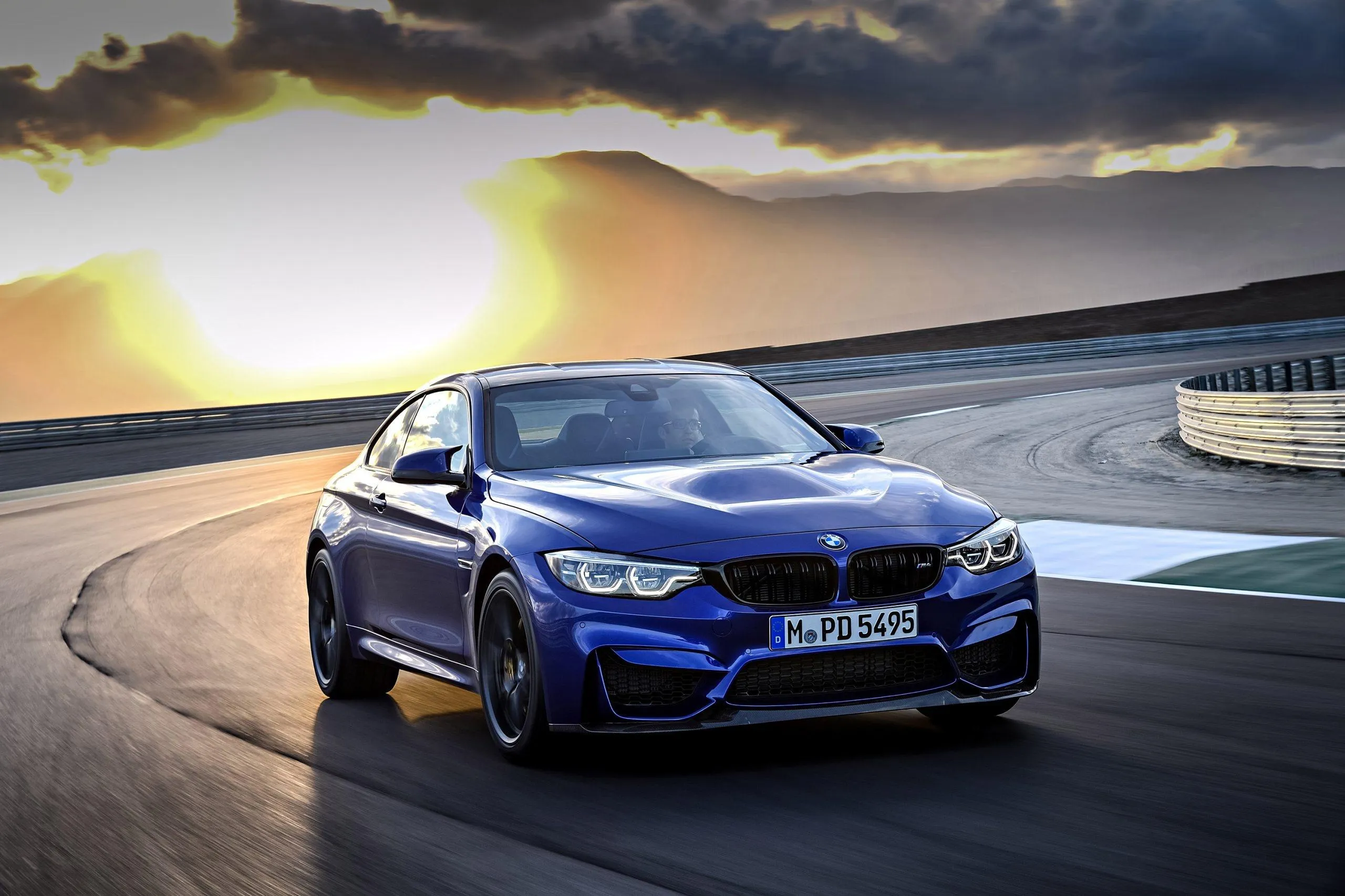 Blue Bmw Racing on a Track with Sunset in the Background