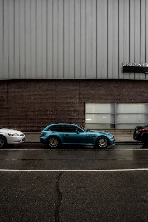 Blue Bmw Sedan Parked By Warehouse Industrial Wall Image