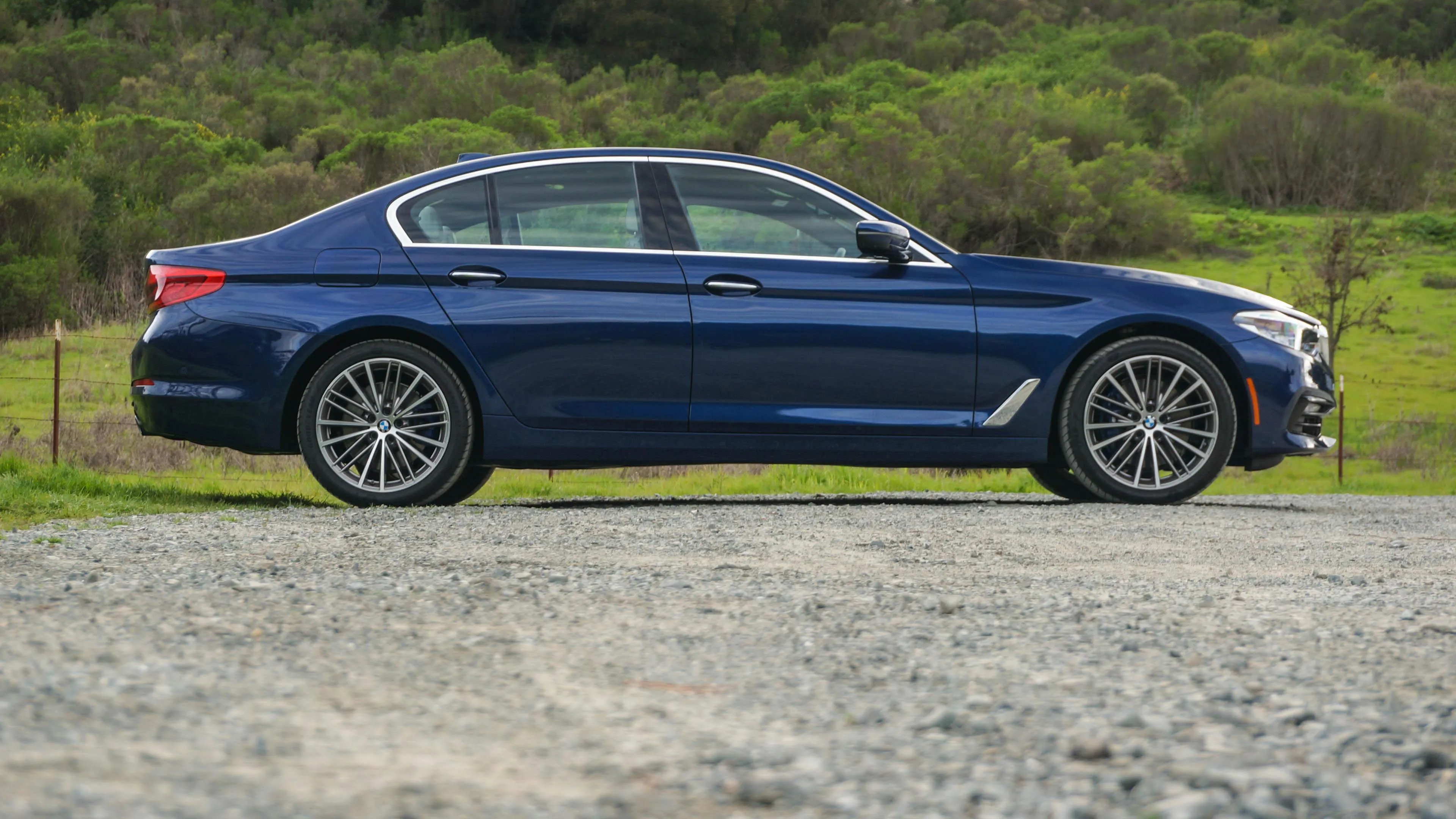 Blue Bmw Sedan Parked on Grassy Roadside Near Clear Sky