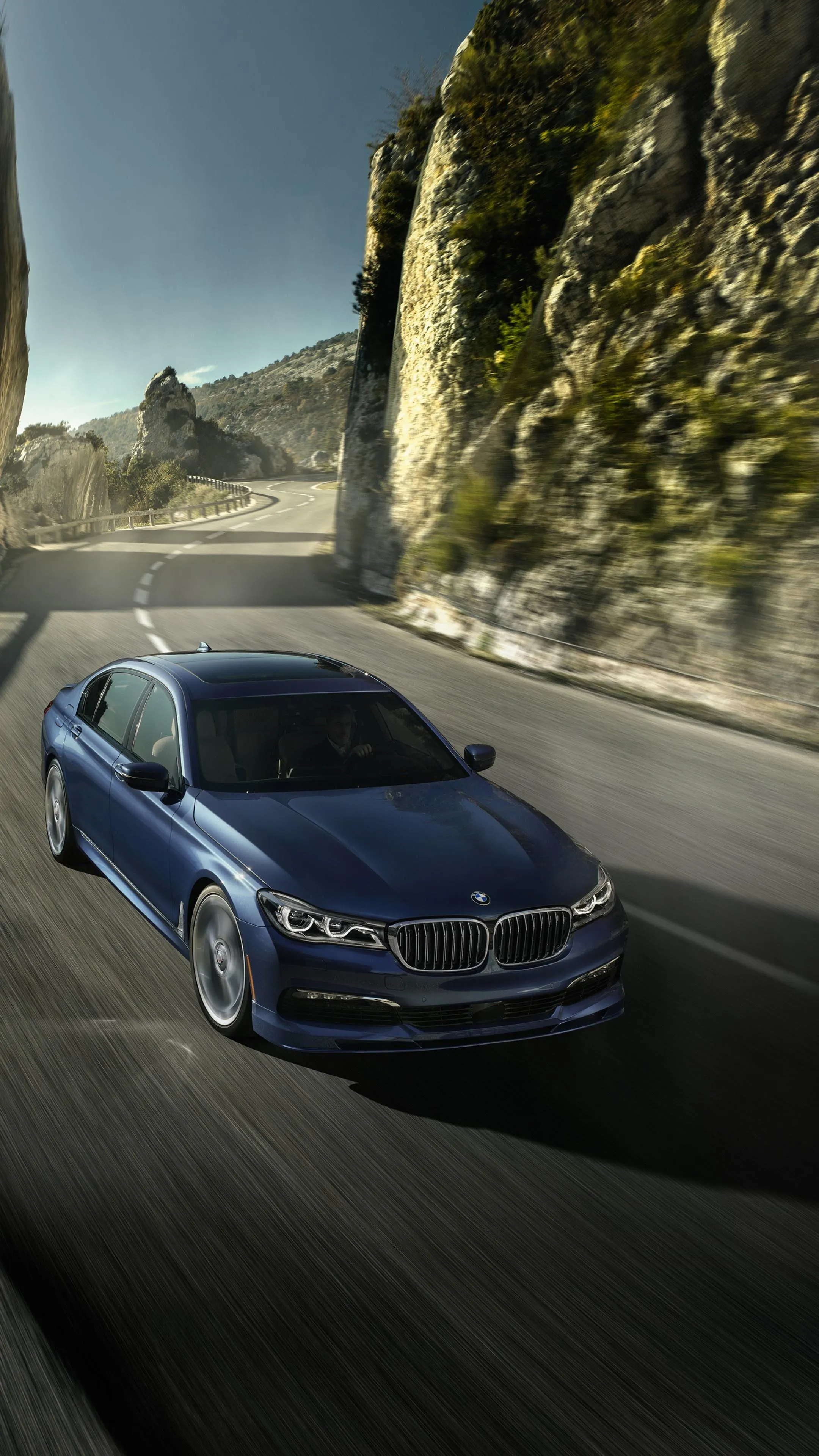 Blue Bmw Speeding Down Winding Road Beside Cliffs