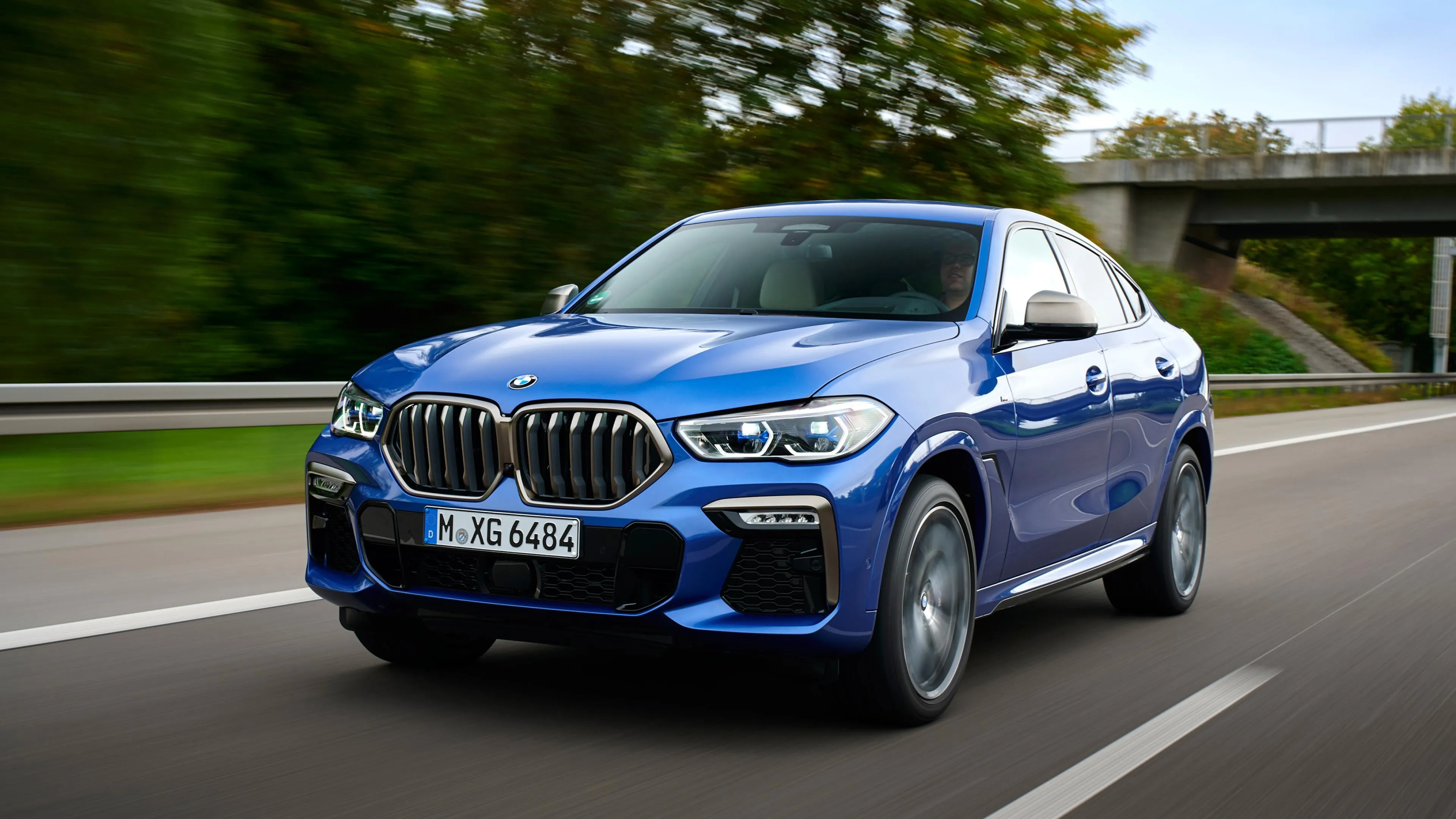 Blue Bmw Suv Cruising on a Tree Lined Suburban Road
