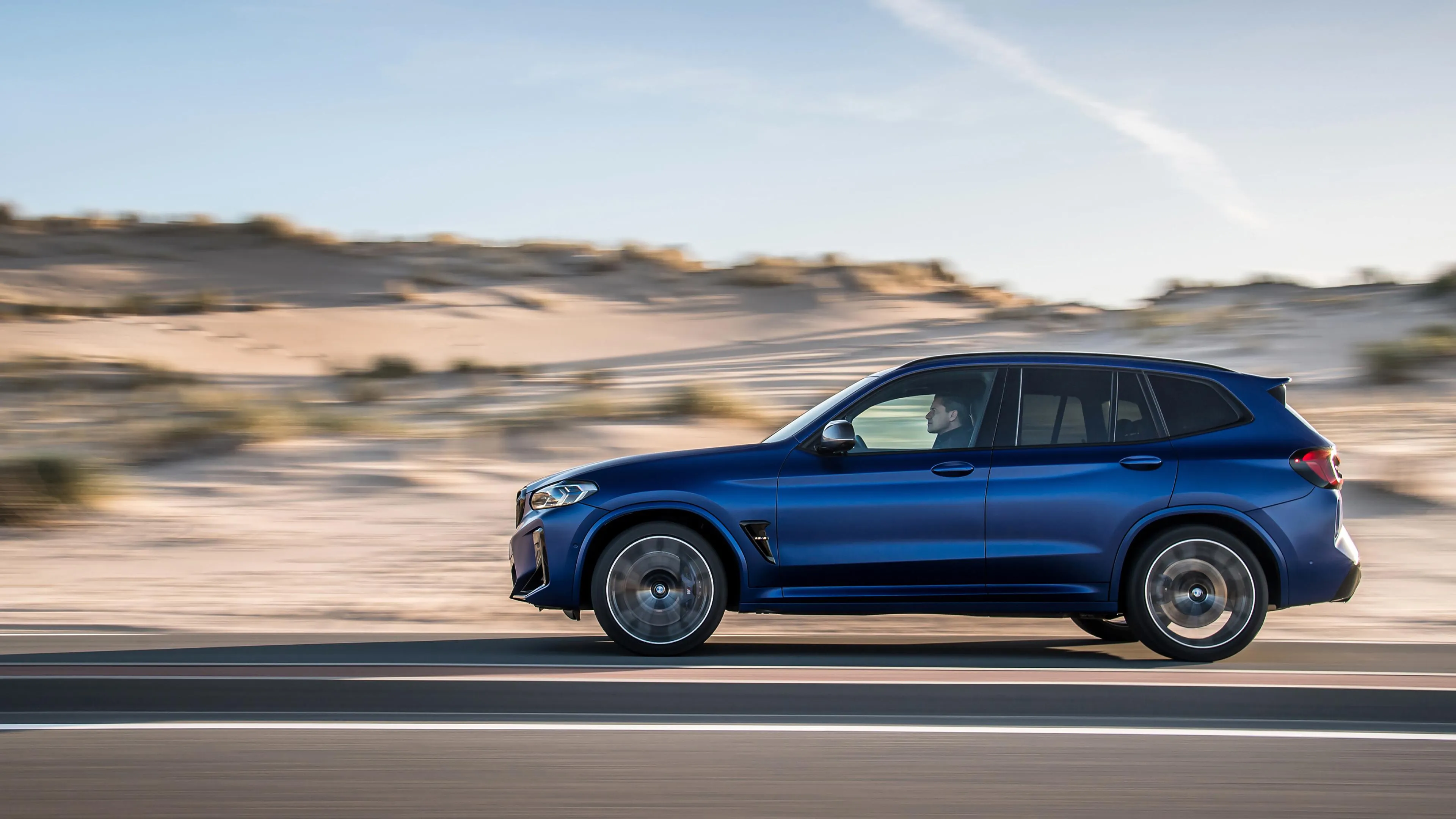 Blue Bmw Suv Driving Along a Desert Road with Dust