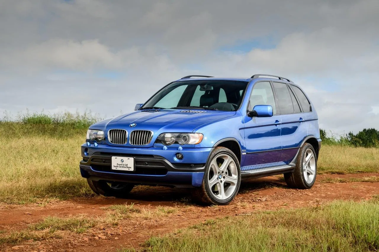 Blue Bmw Suv Driving on Dirt Road in Open Rural Field