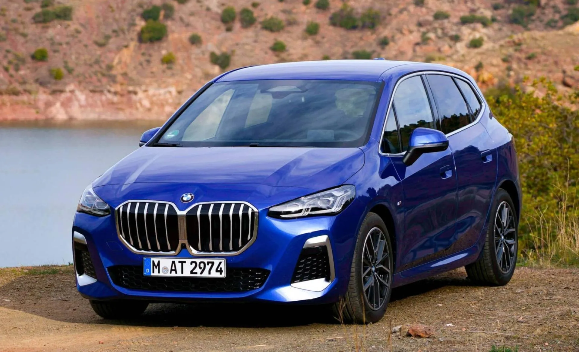 Blue Bmw Suv Parked Near a Lake with Hills in the Background