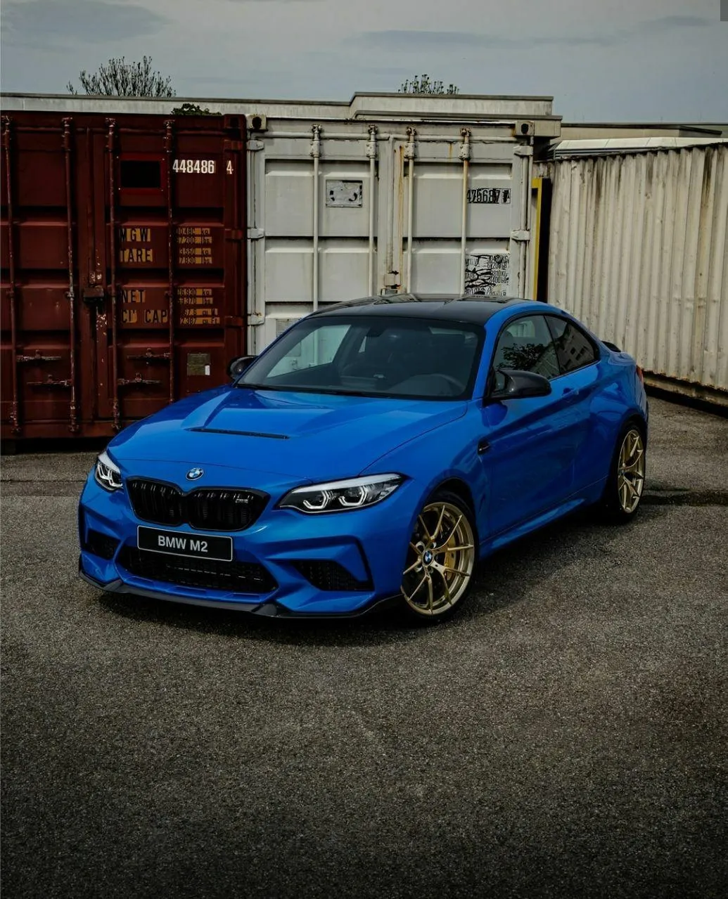 Bmw Blue Sedan Parked Near Shipping Containers