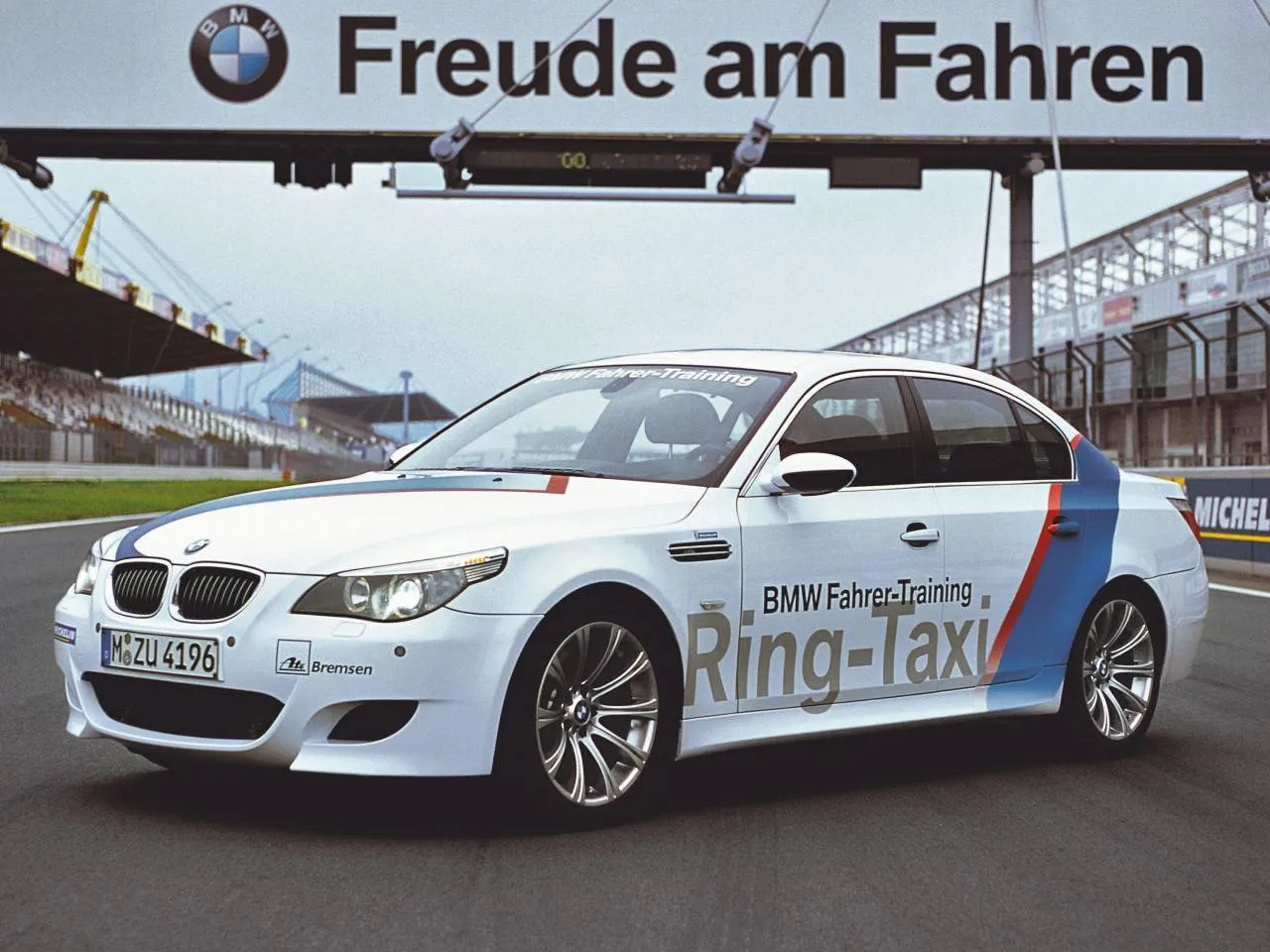 Bmw Car with a Logo Near a Racetrack with Audience Around
