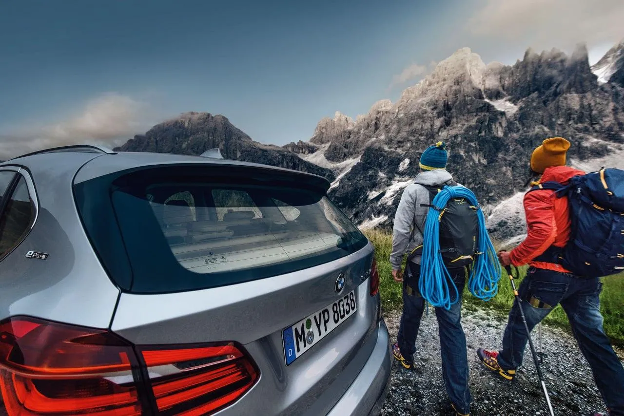Bmw Car with Hikers in the Background Near a Mountain