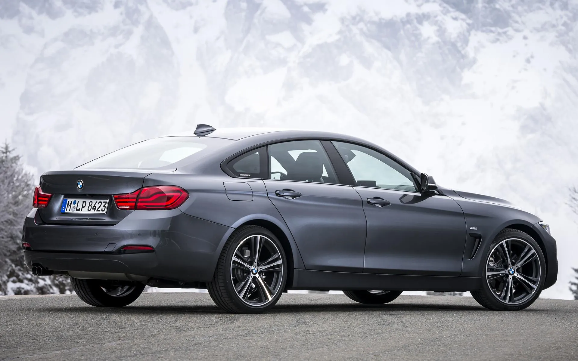 Bmw Coupe Driving on Snow Covered Road with Rugged Mountains