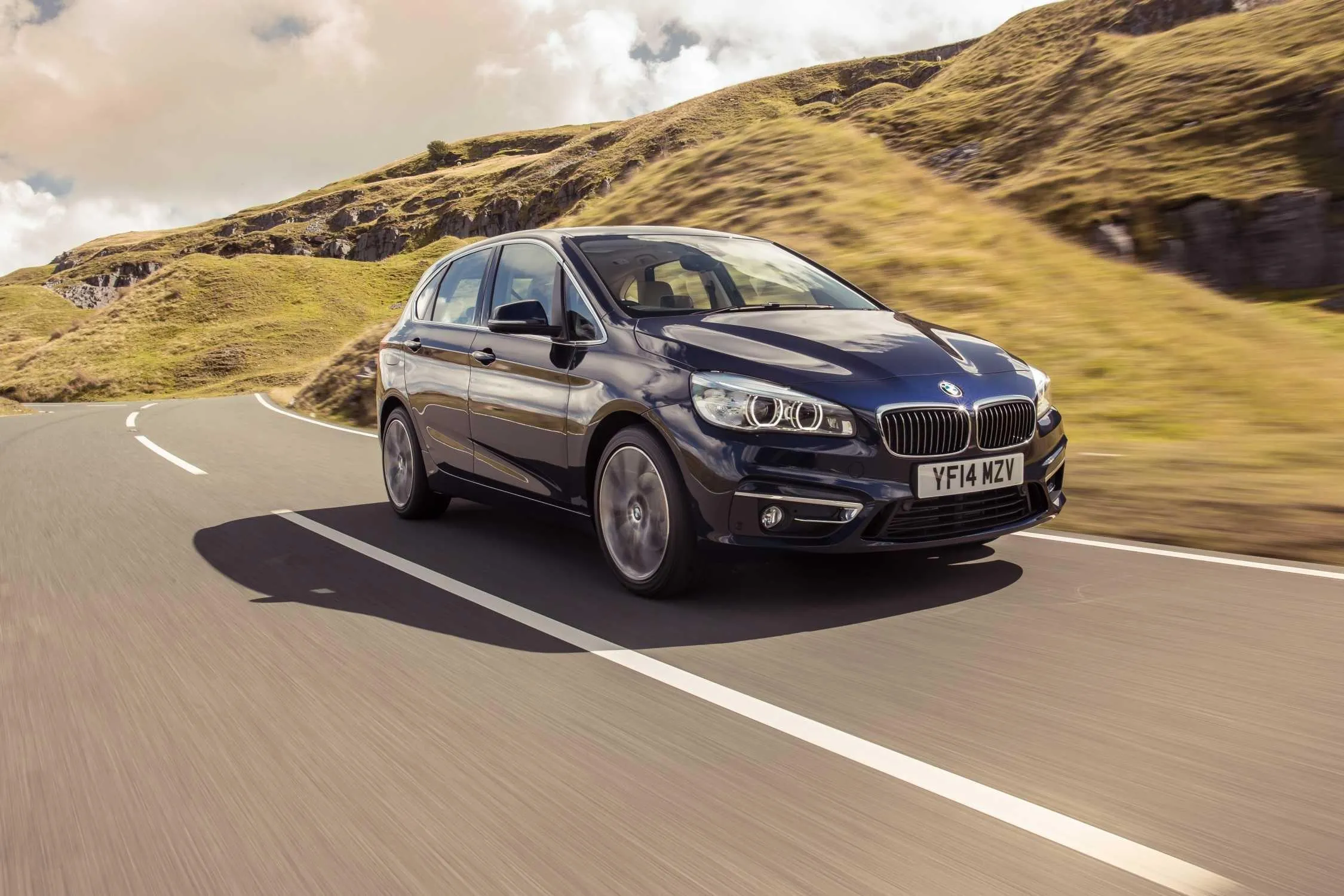 Bmw Driving Fast on Winding Road in Hilly Landscape Image