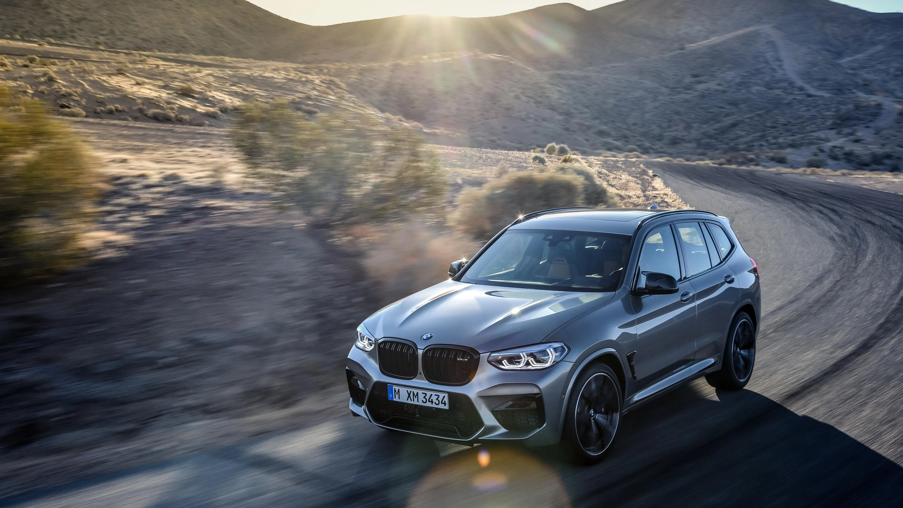 Bmw Driving on Mountain Road at Golden Sunset Wallpaper