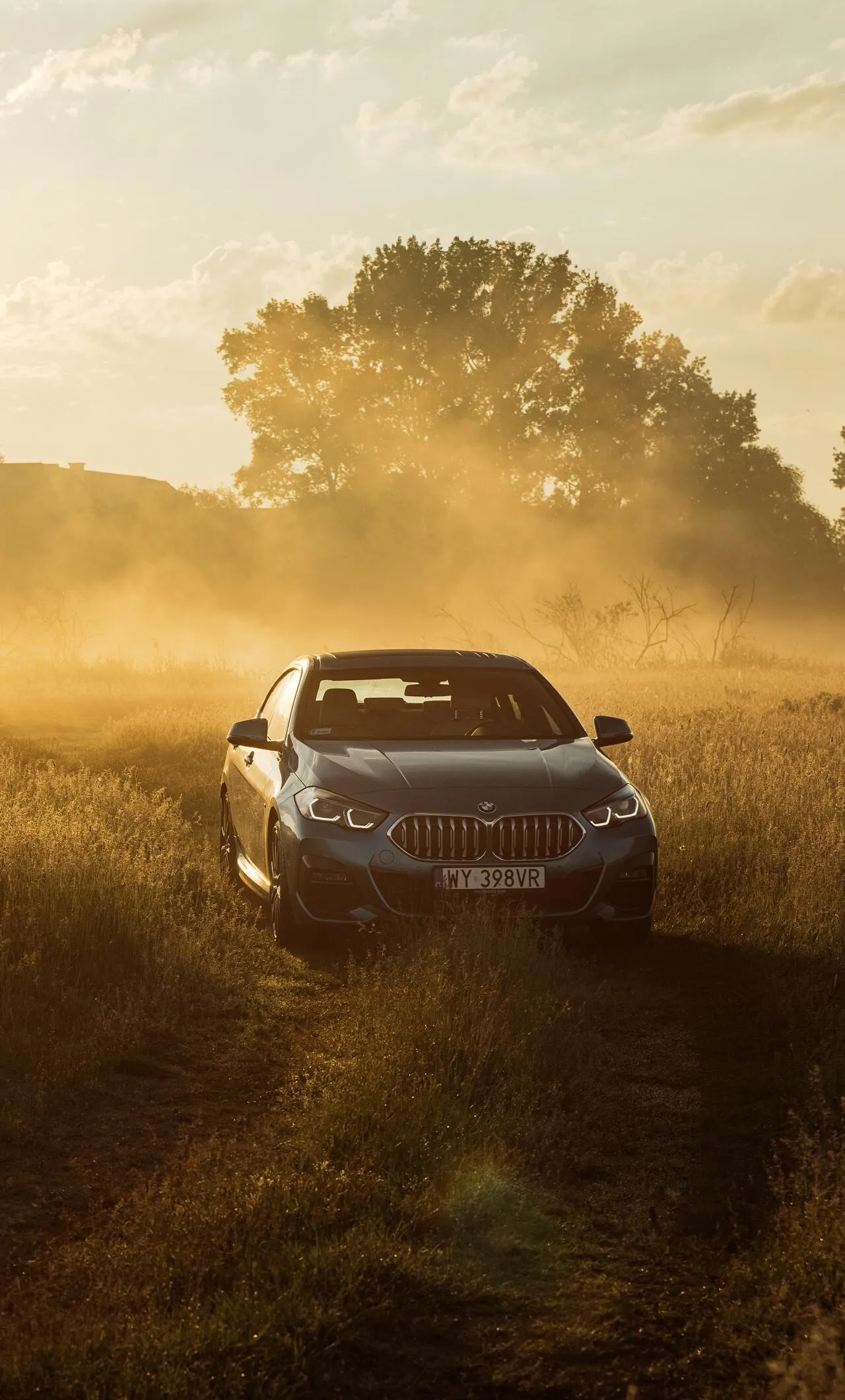 Bmw Driving Through Dusty Offroad Trail at Sunset Wallpaper