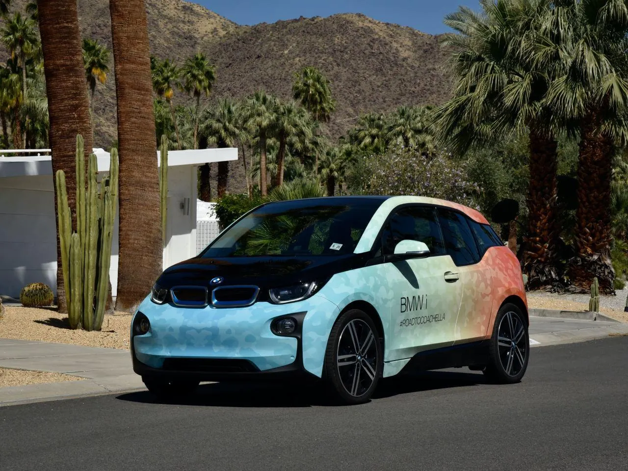 Bmw I3 with a Colorful Design on the Road with Scenic Backdrop