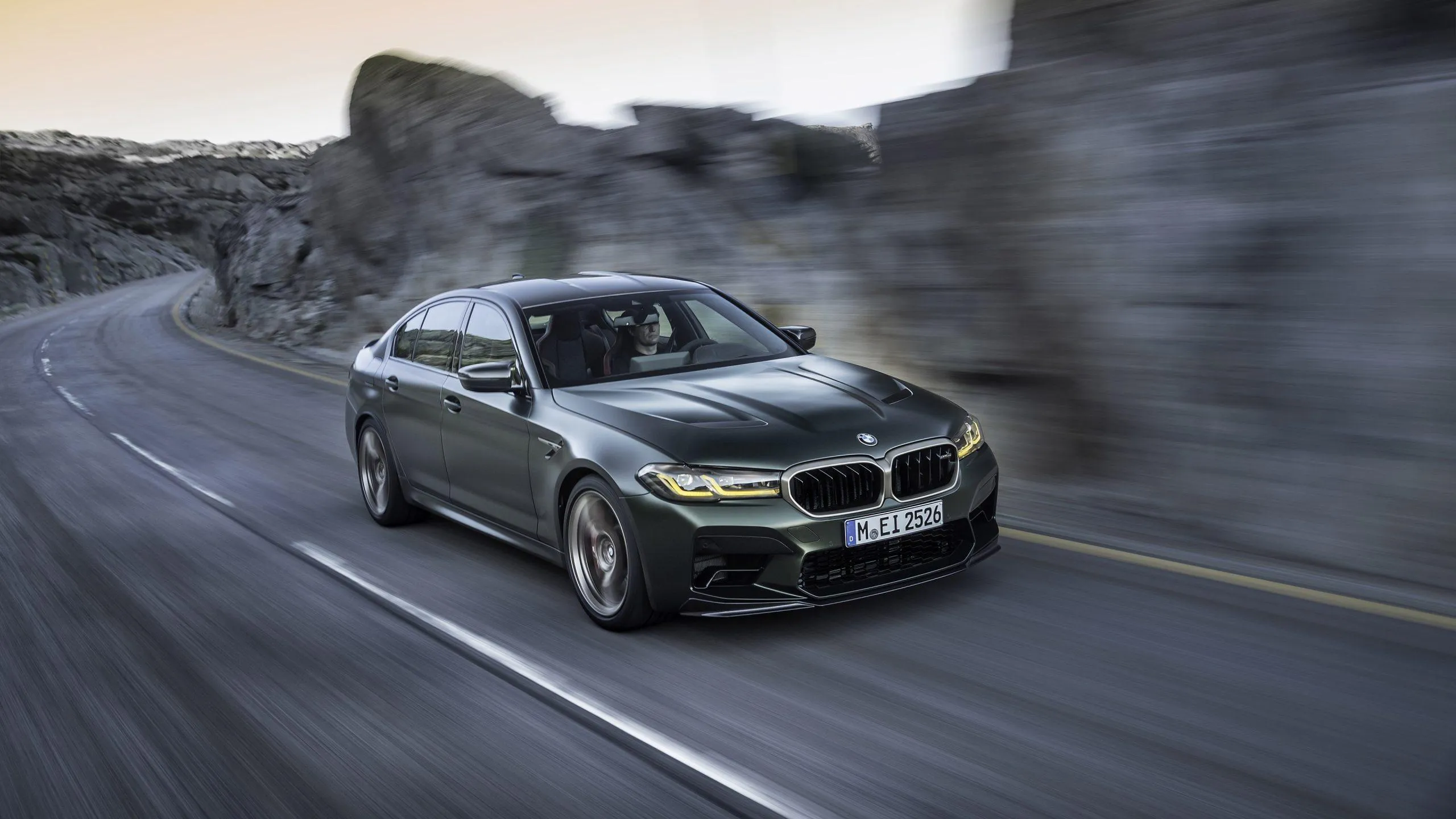 Bmw Luxury Car Speeding on Mountain Road Wallpaper