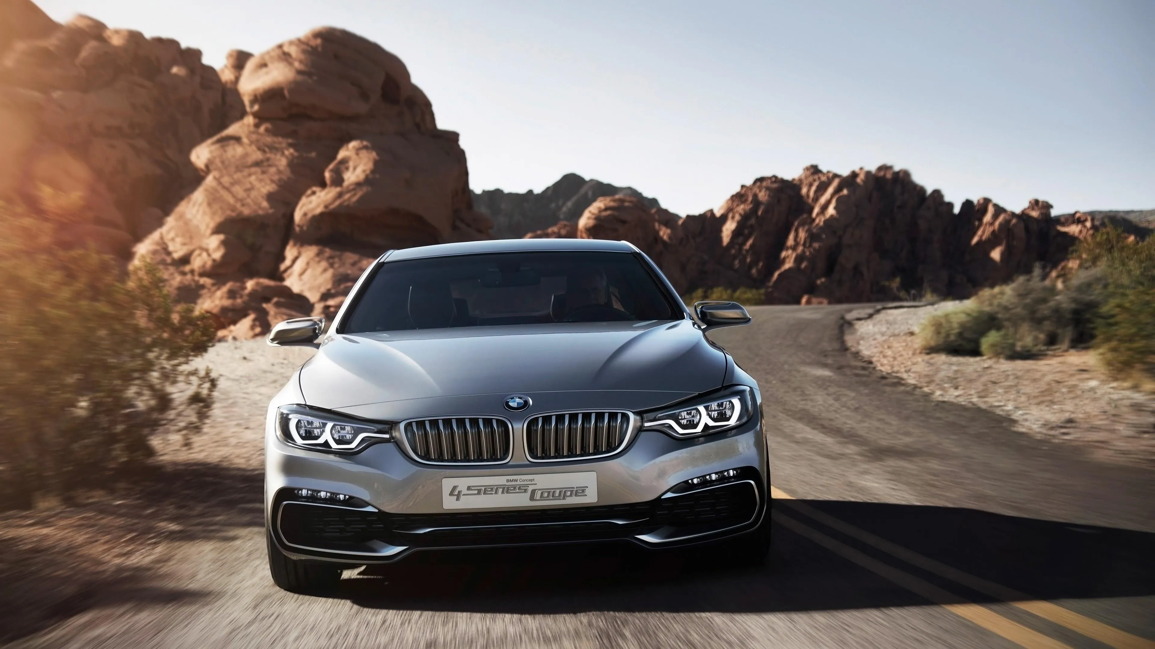 Bmw on Desert Road with Large Rocks and Mountains Around
