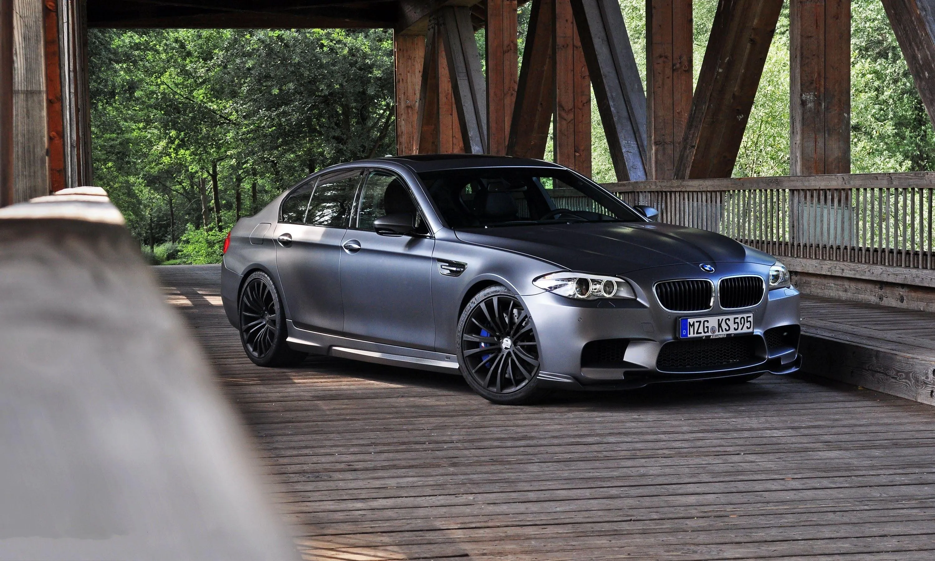 Bmw Parked on Wooden Bridge in a Forested Area Wallpaper
