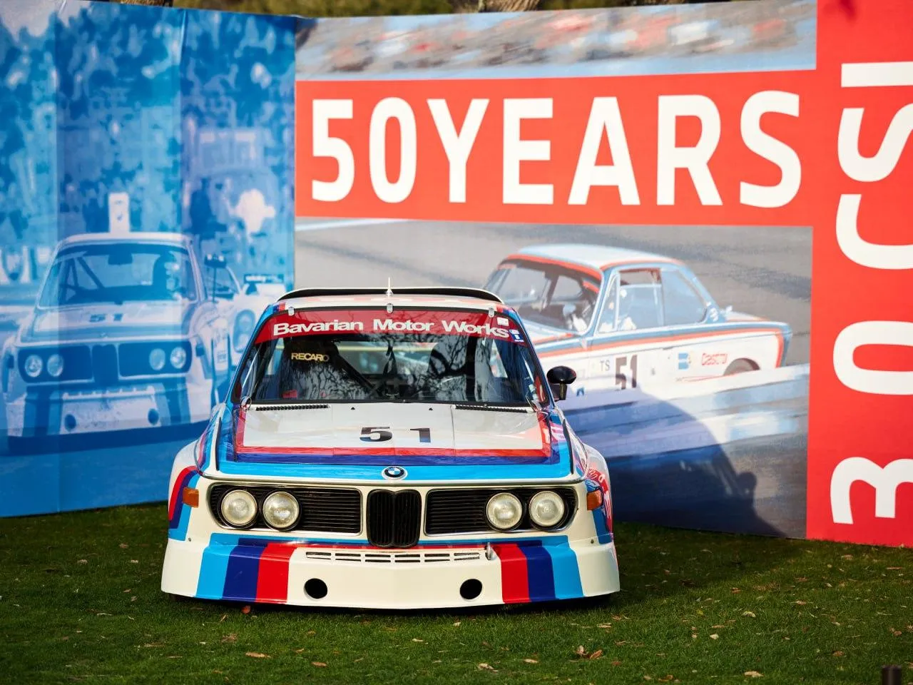 Bmw Race Car Displayed at Motorsport Event with Red Banner