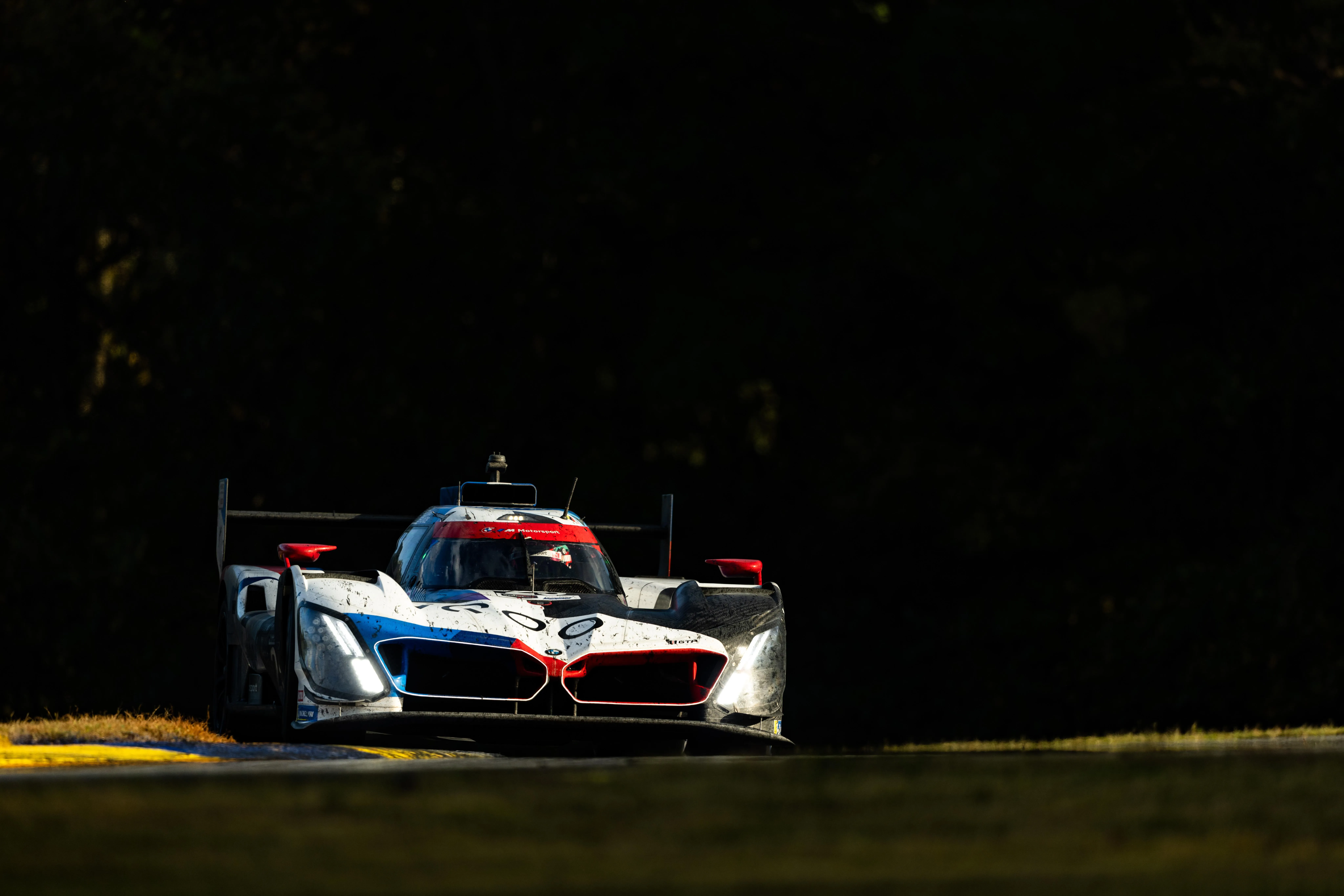 Bmw Race Car Parked in Shadow with Headlights on Wallpaper