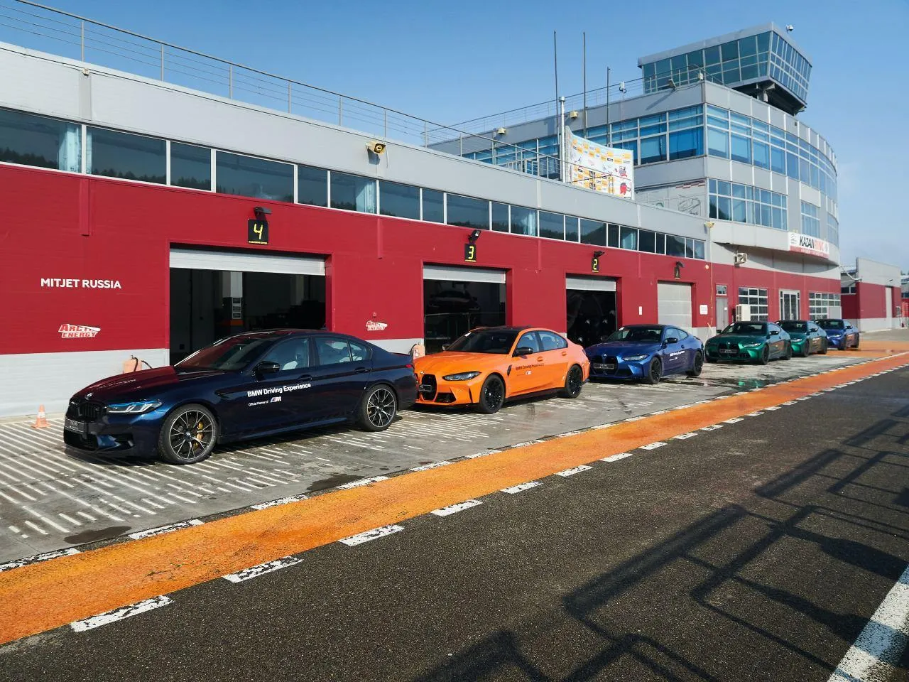 Bmw Race Cars in Pit Lane with Multiple Cars and Red Garages