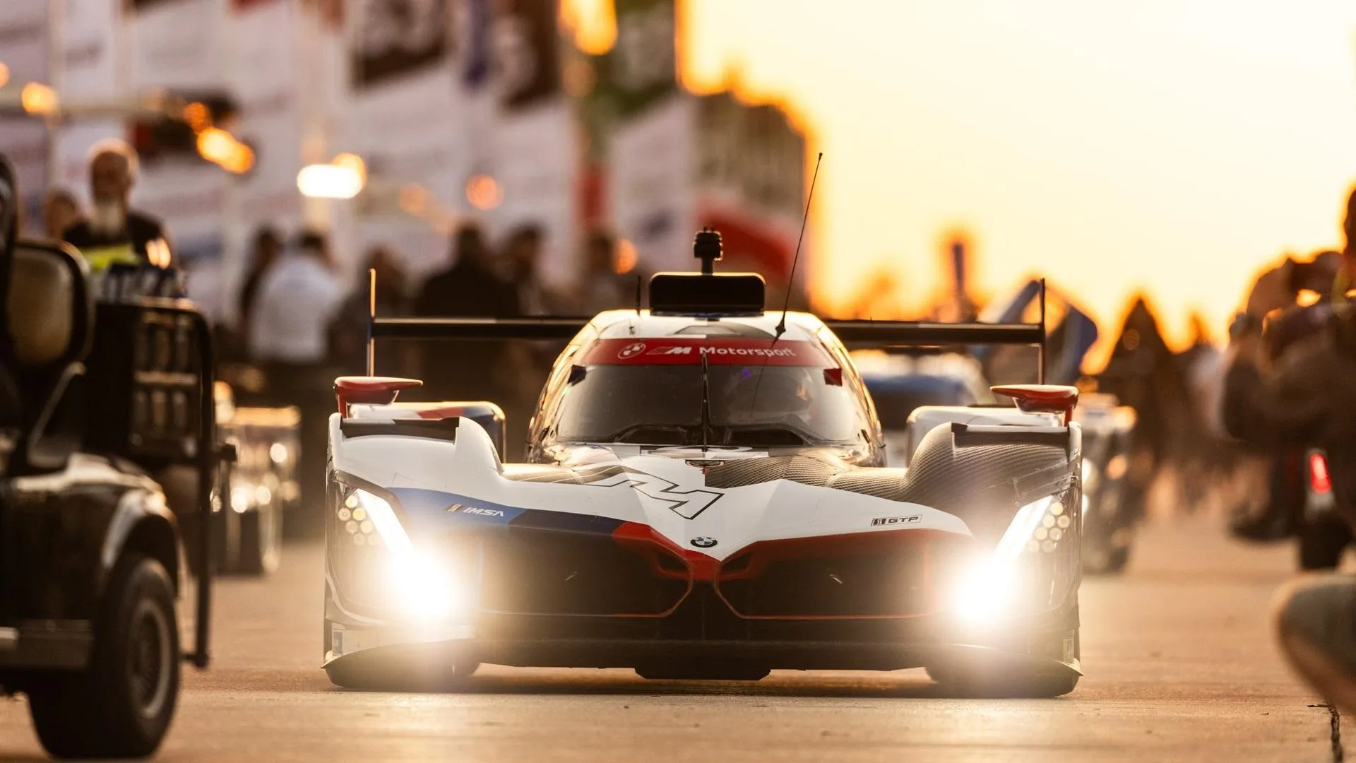 Bmw Racing Car in Action with Pit Crew Present Wallpaper