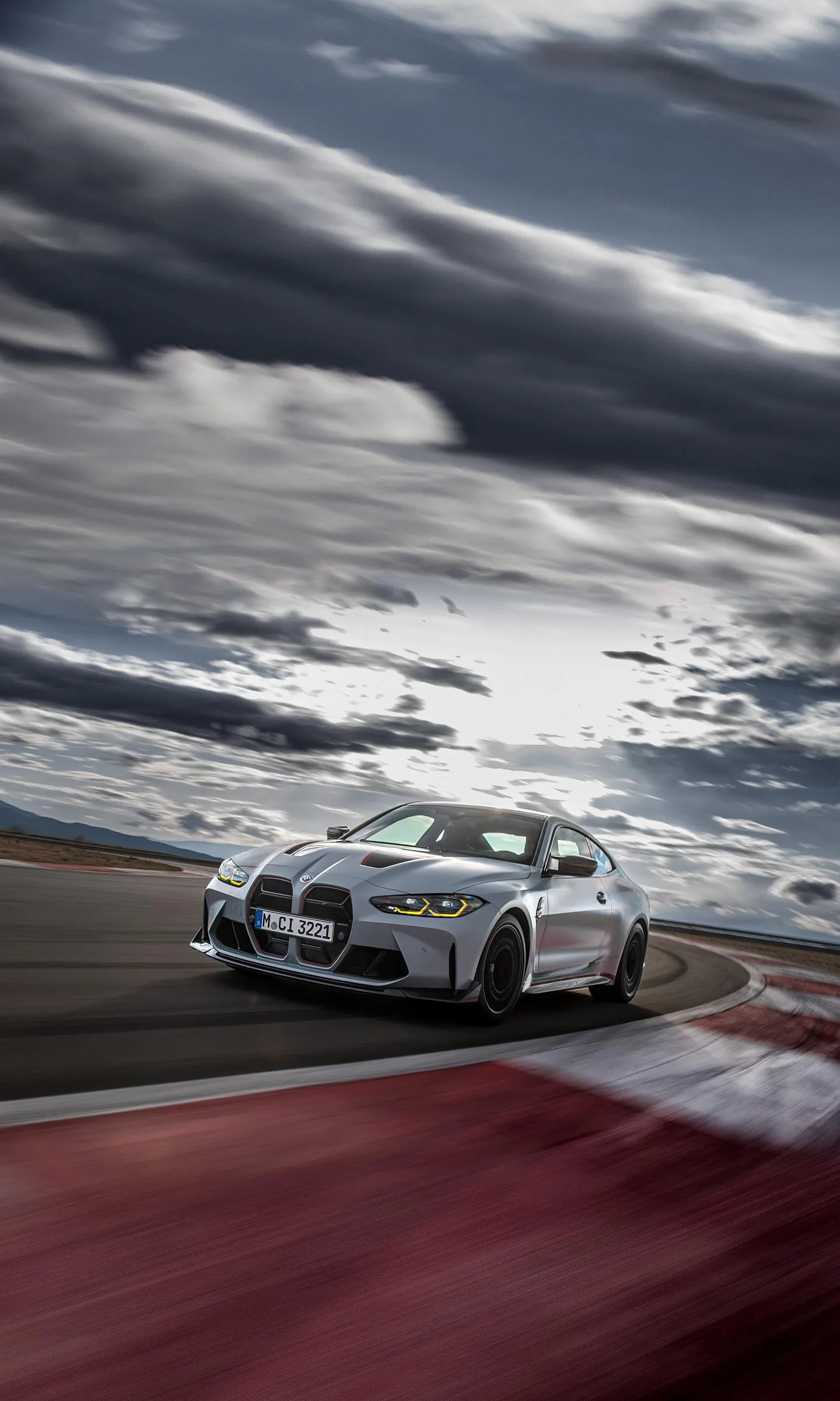 Bmw Racing Car on Track Under Dramatic Cloudy Sky Wallpaper