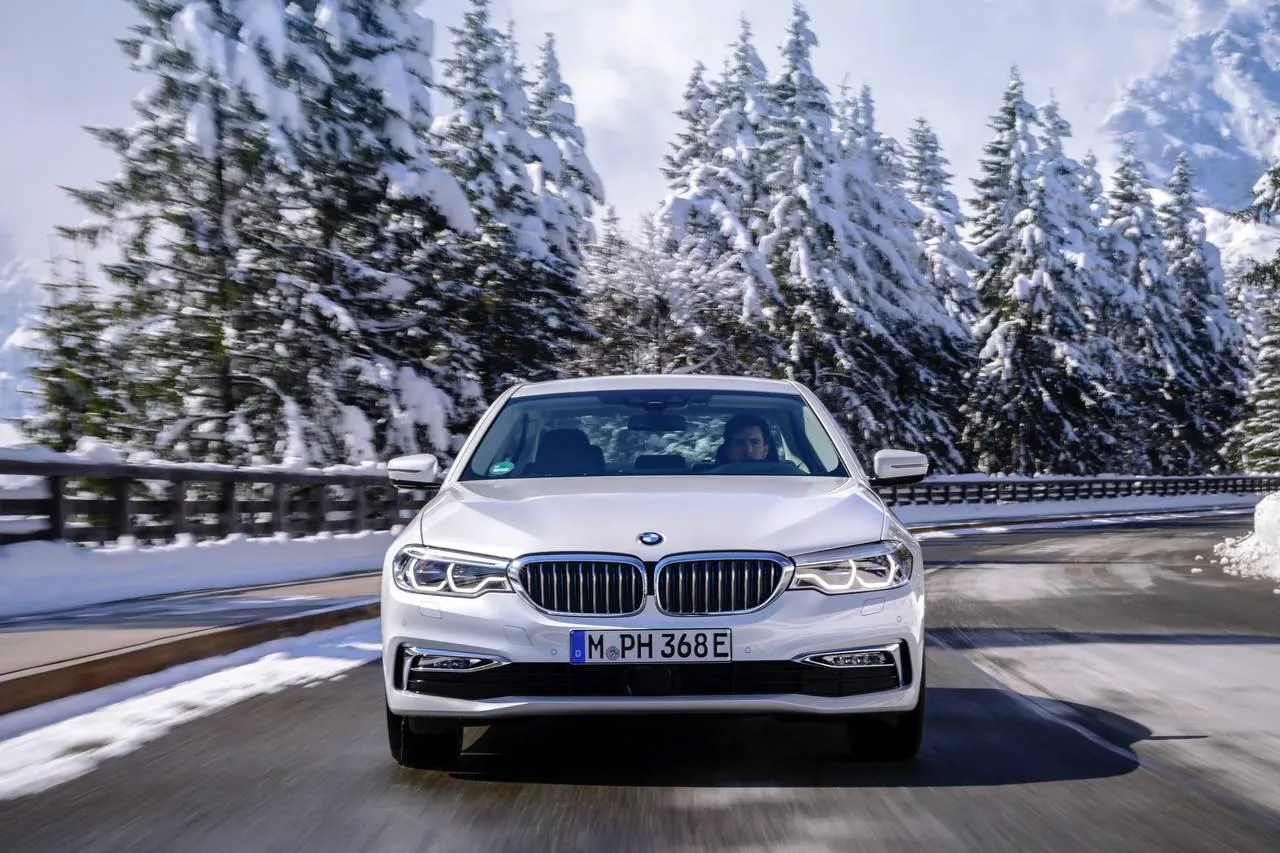 Bmw Sedan Driving on Snowy Road with Scenic Mountains