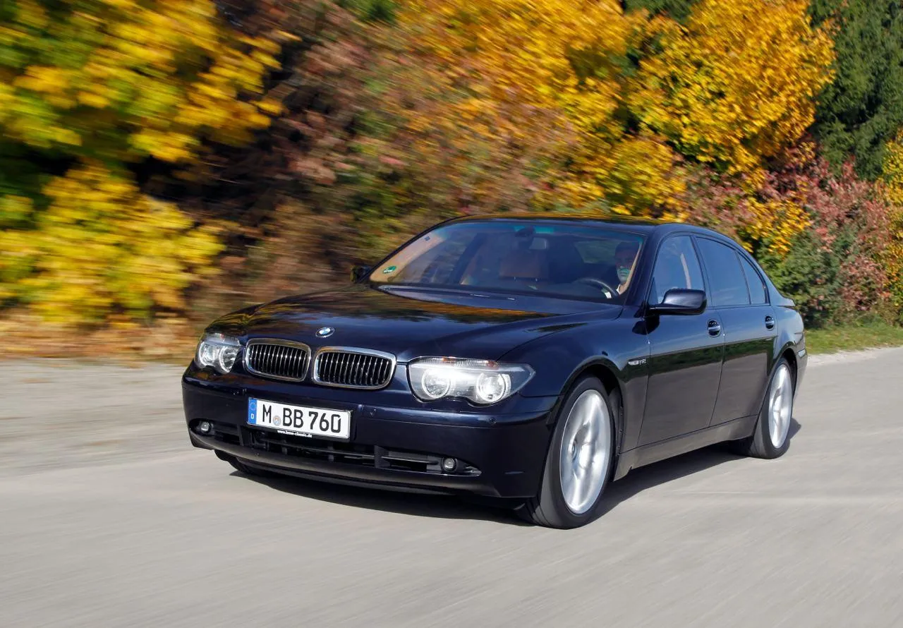 Bmw Sedan Driving Through Scenic Autumn Road Path Wallpaper